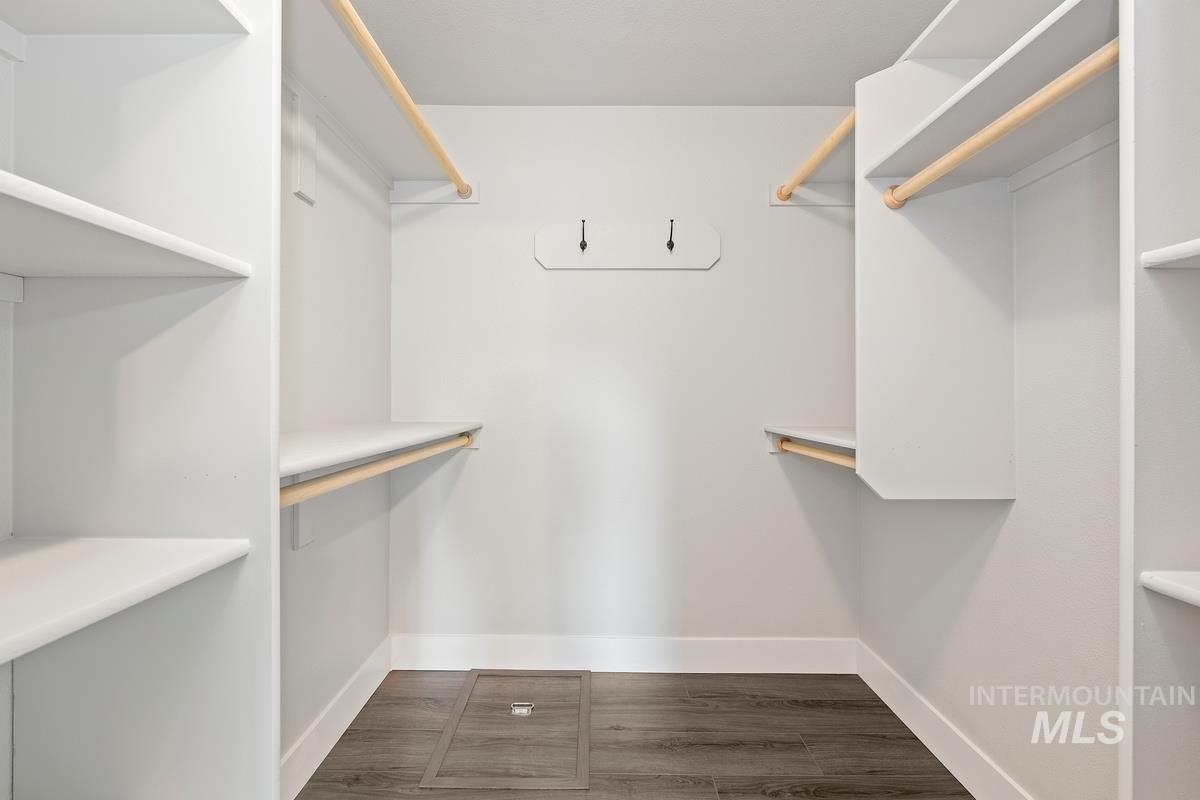 Walk in closet with dark wood-type flooring