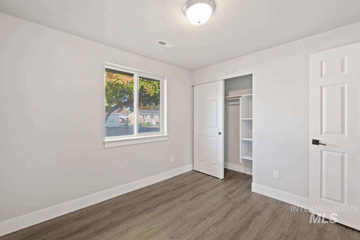 Unfurnished bedroom with wood finished floors and a closet