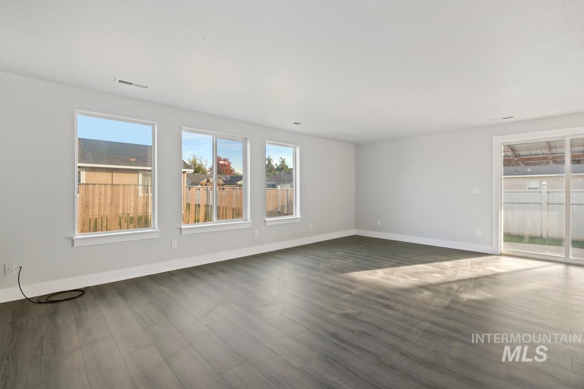 Unfurnished living room featuring plenty of natural light and dark wood finished floors