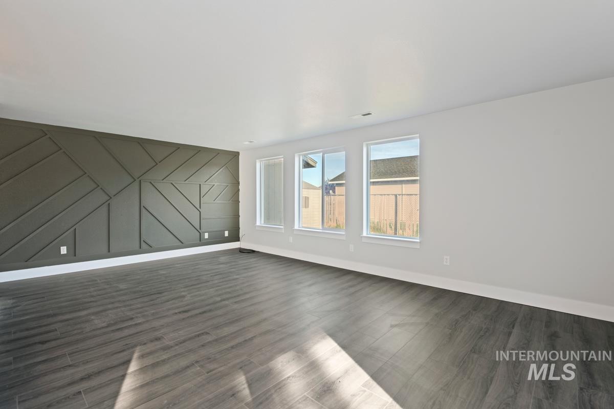 Unfurnished living room with wood finished floors and a decorative wall