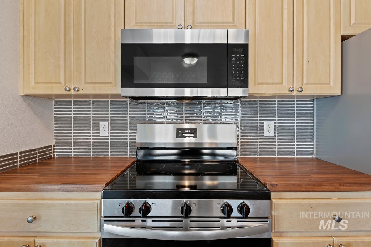 Kitchen featuring butcher block countertops, stainless steel appliances, and light brown cabinetry
