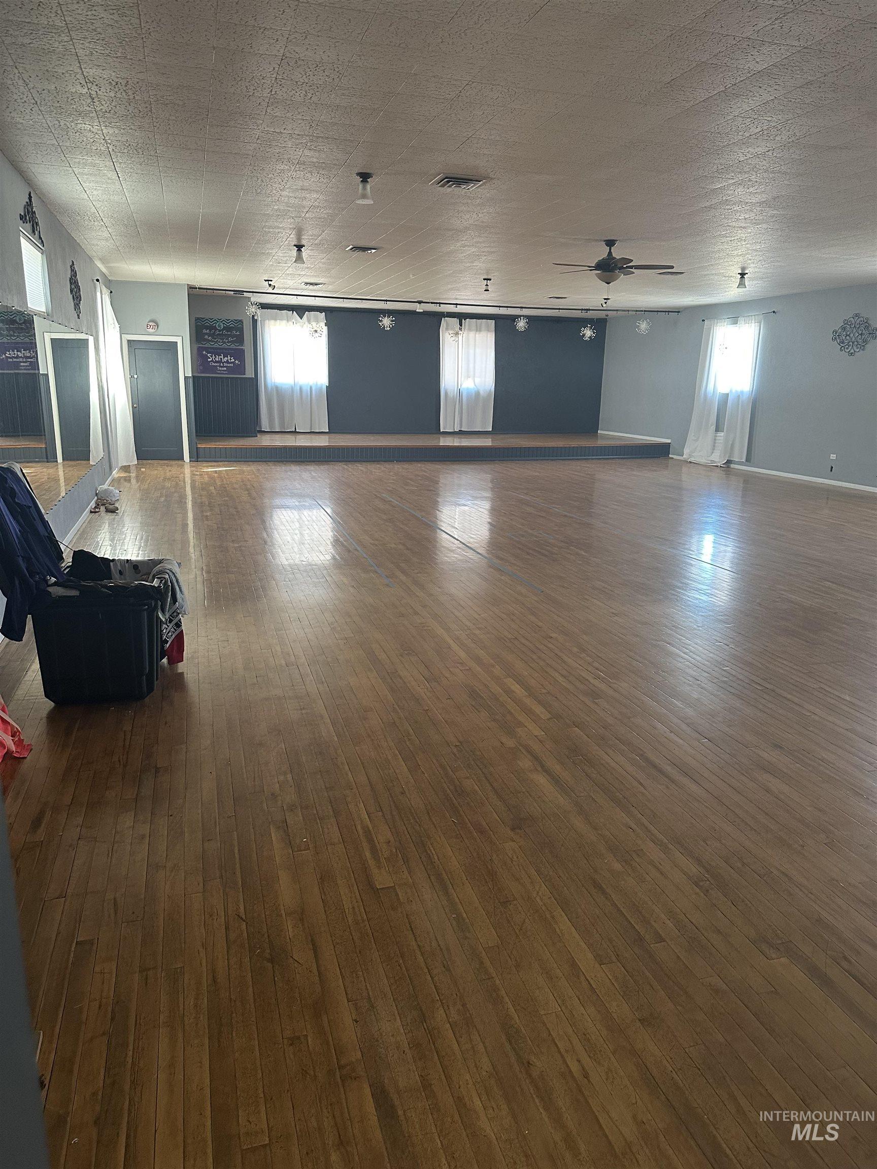 Unfurnished living room with dark wood-style floors and a ceiling fan