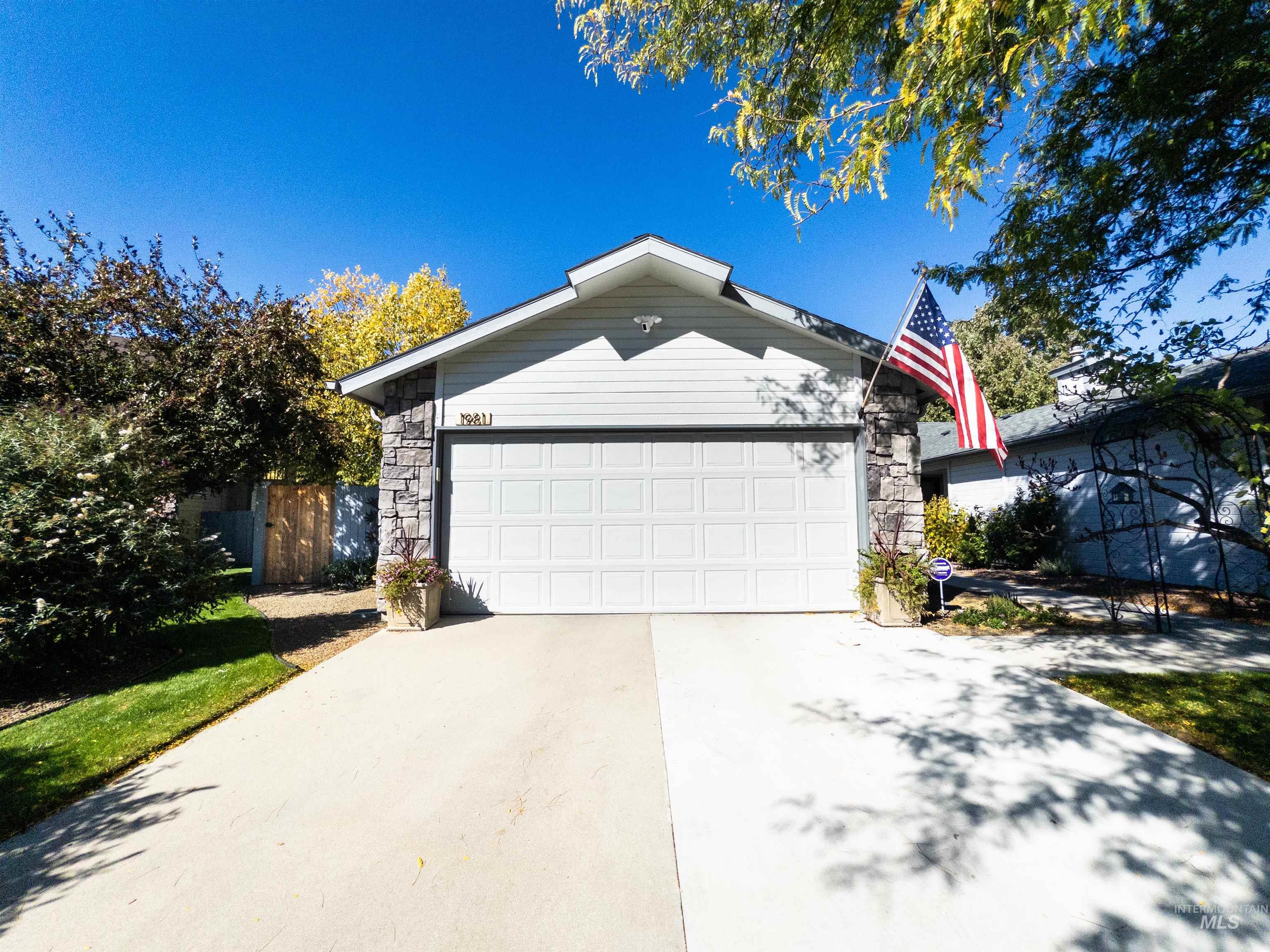 View of front of property with driveway, stone siding, and a garage
