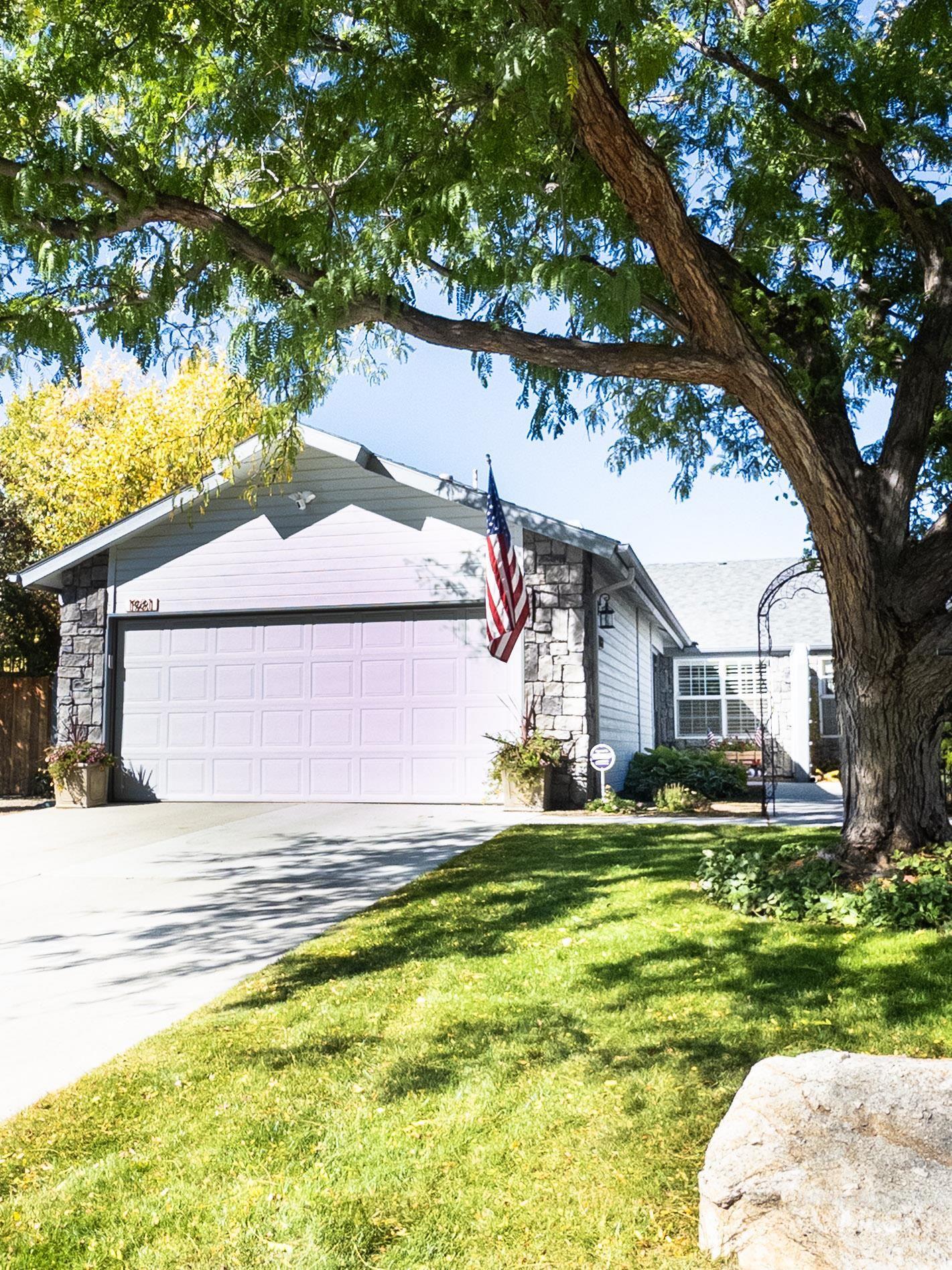 Single story home with stone siding, driveway, a front lawn, and an attached garage