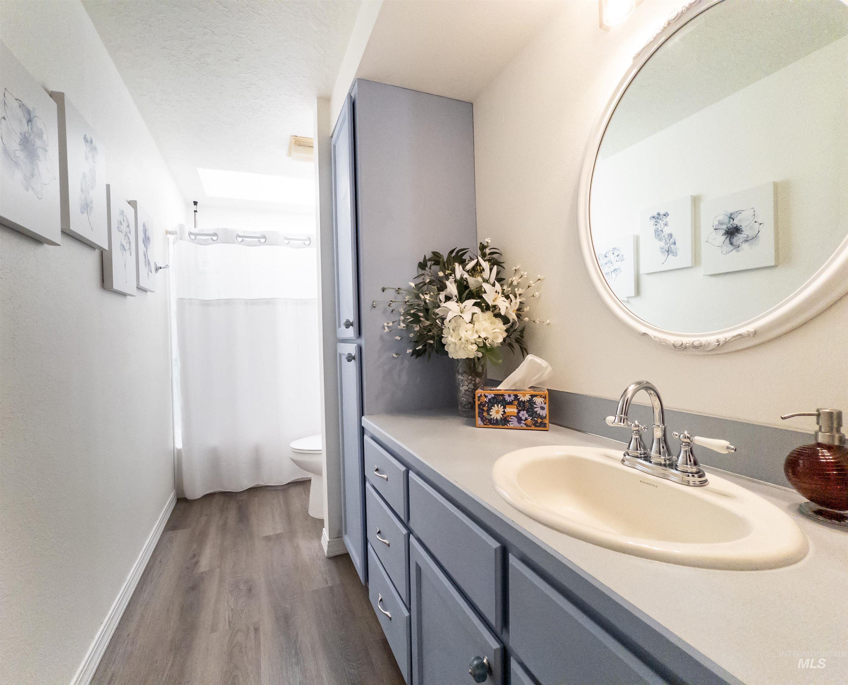 Bathroom featuring vanity, dark wood-type flooring, shower / tub combo with curtain, and a textured ceiling