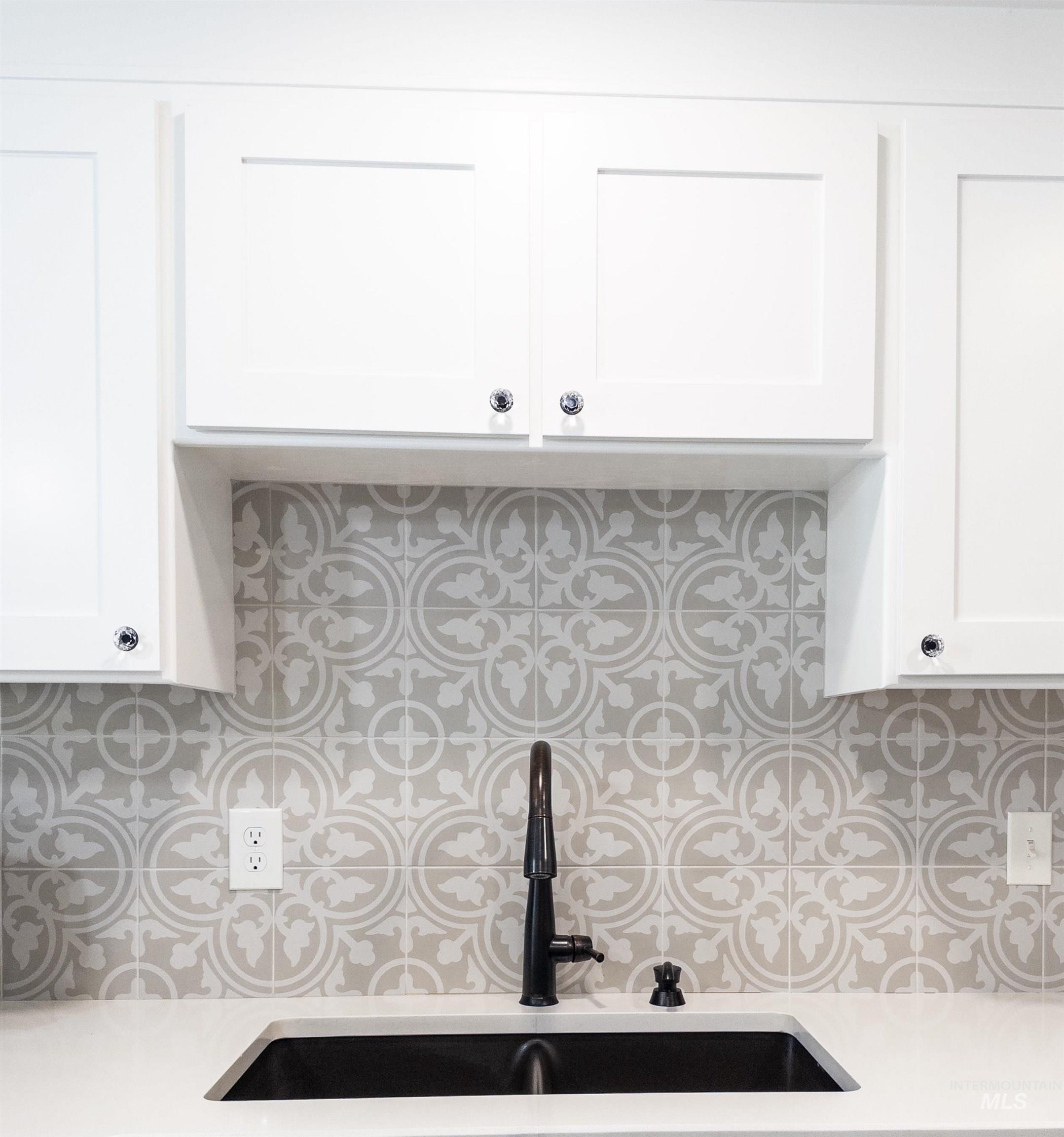 Kitchen view of white cabinetry, tasteful backsplash, and light stone counters