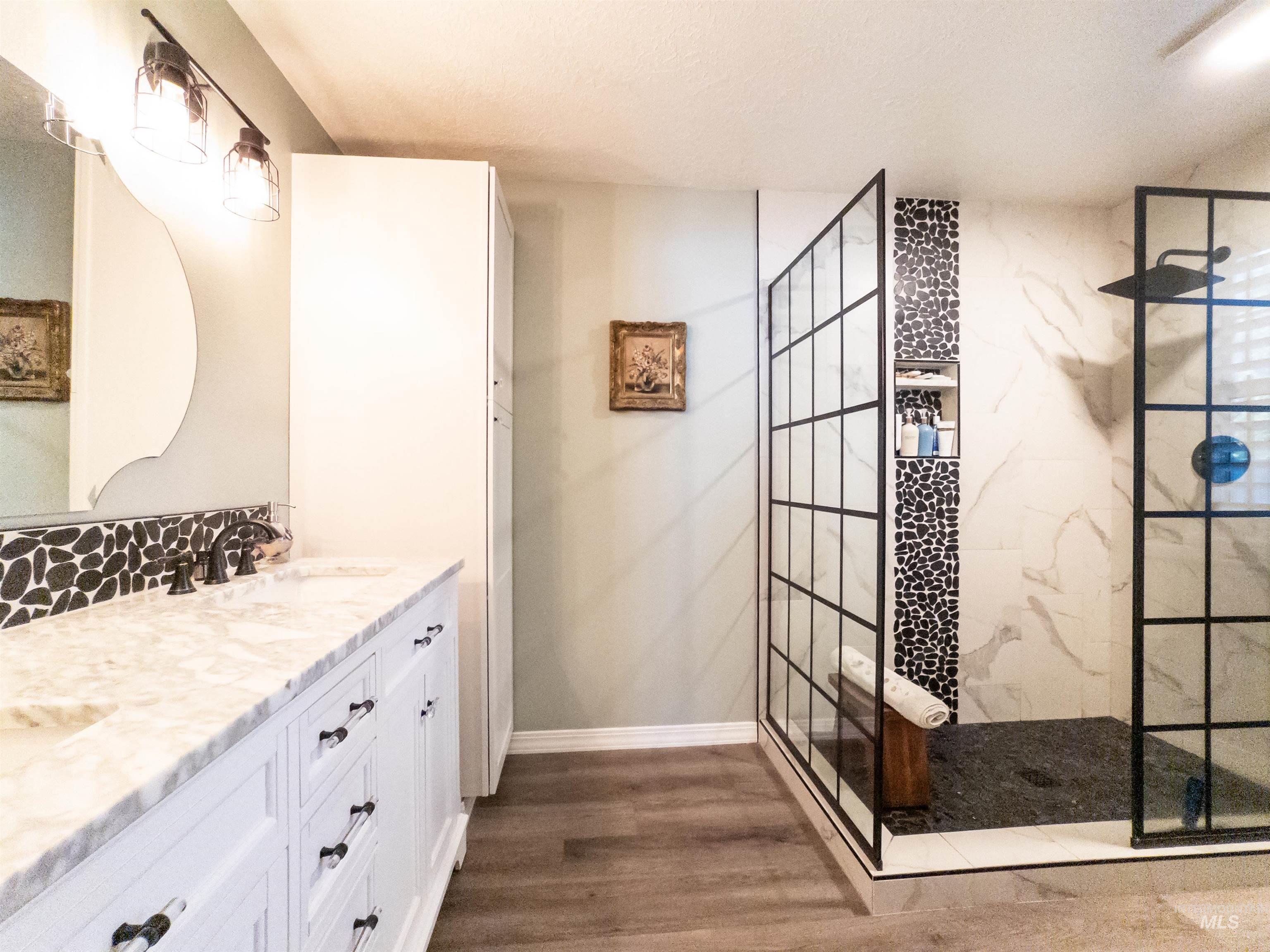 Bathroom with a marble finish shower, vanity, dark wood finished floors, and a textured ceiling