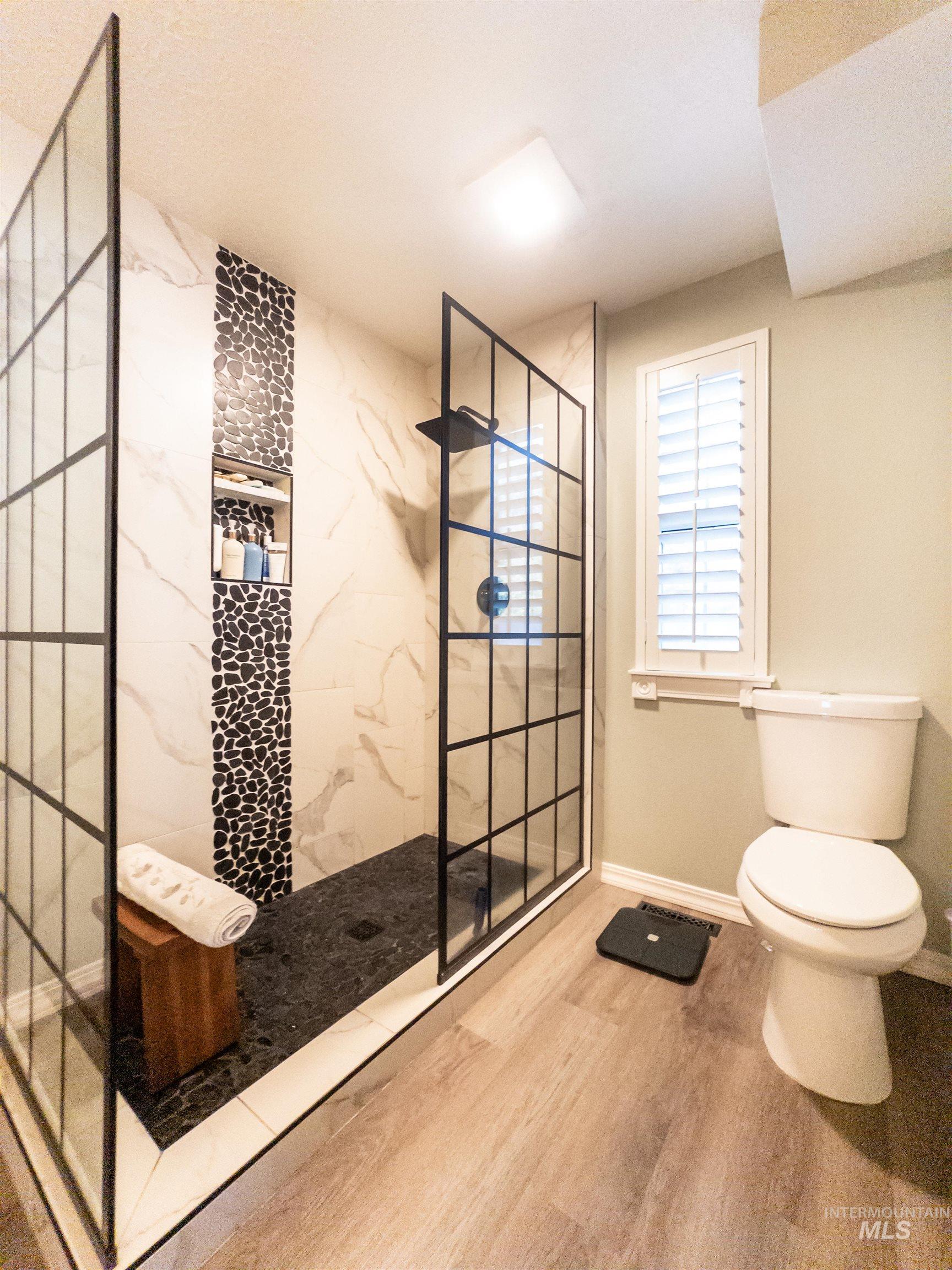 Full bathroom with a marble finish shower and wood finished floors