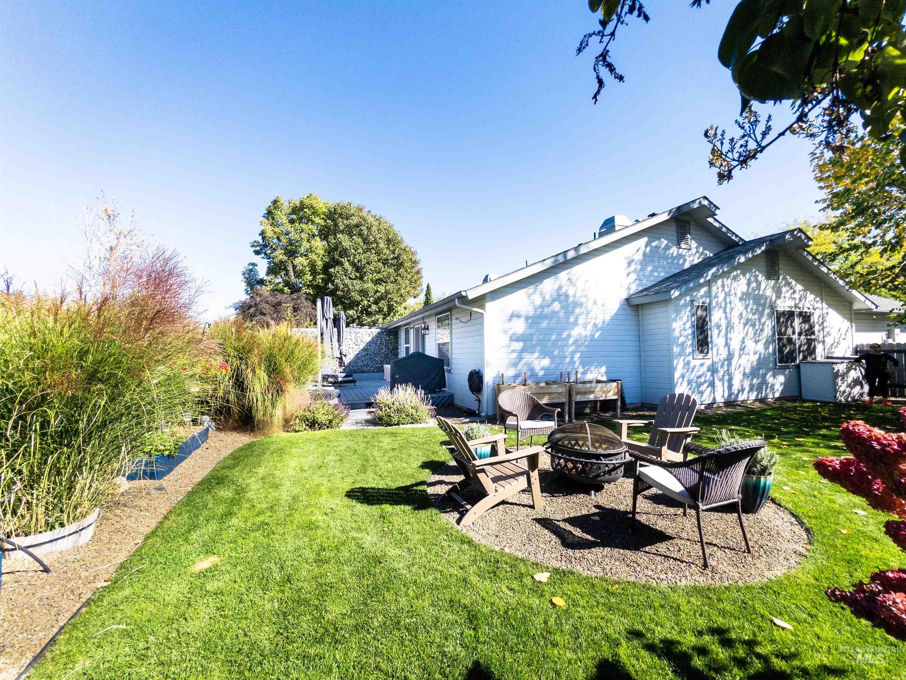 View of green lawn featuring a patio and a fire pit