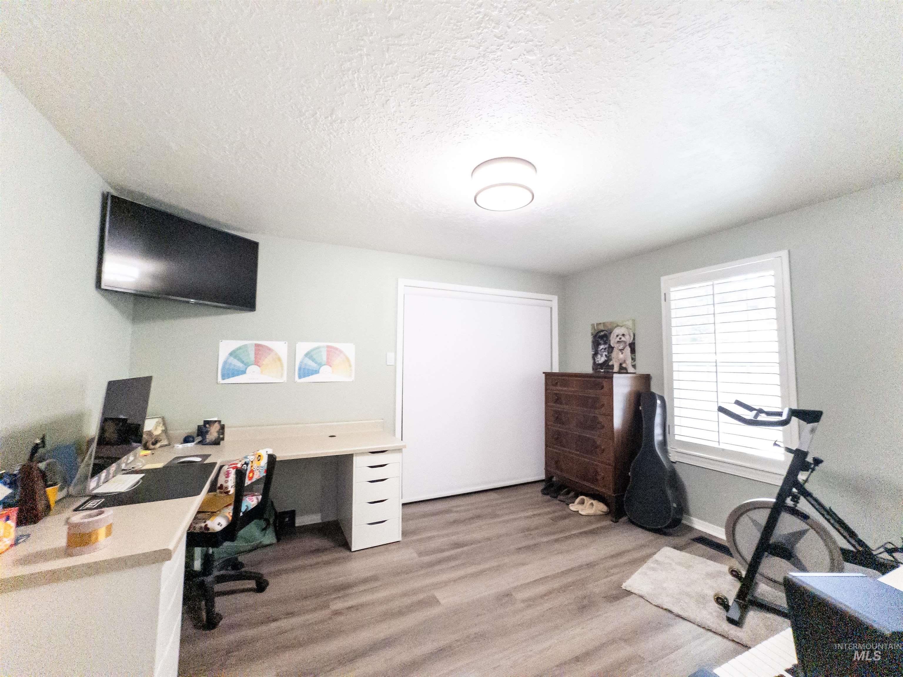 Office space featuring light wood-style flooring and a textured ceiling