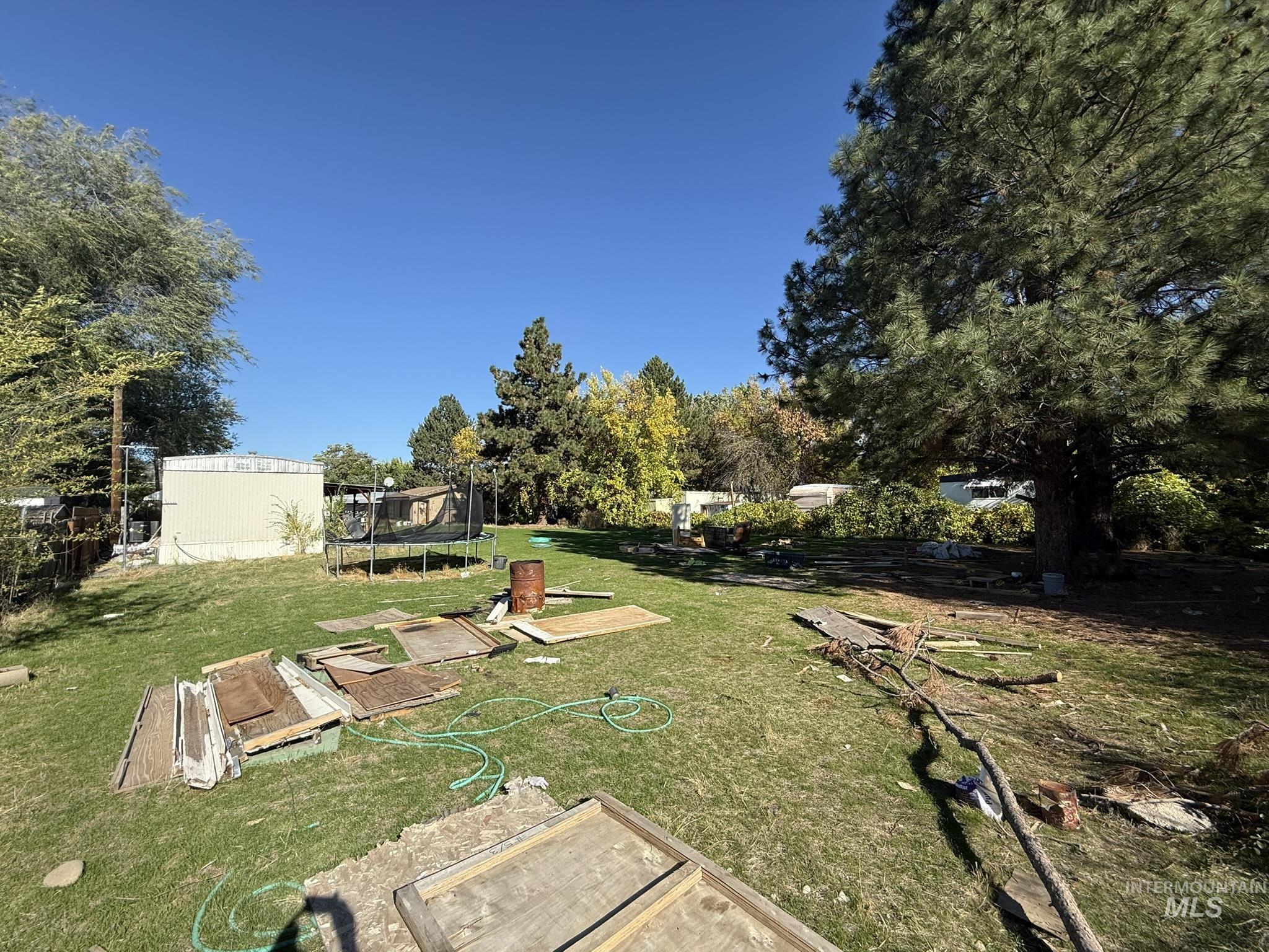 View of green lawn featuring a trampoline and an outbuilding