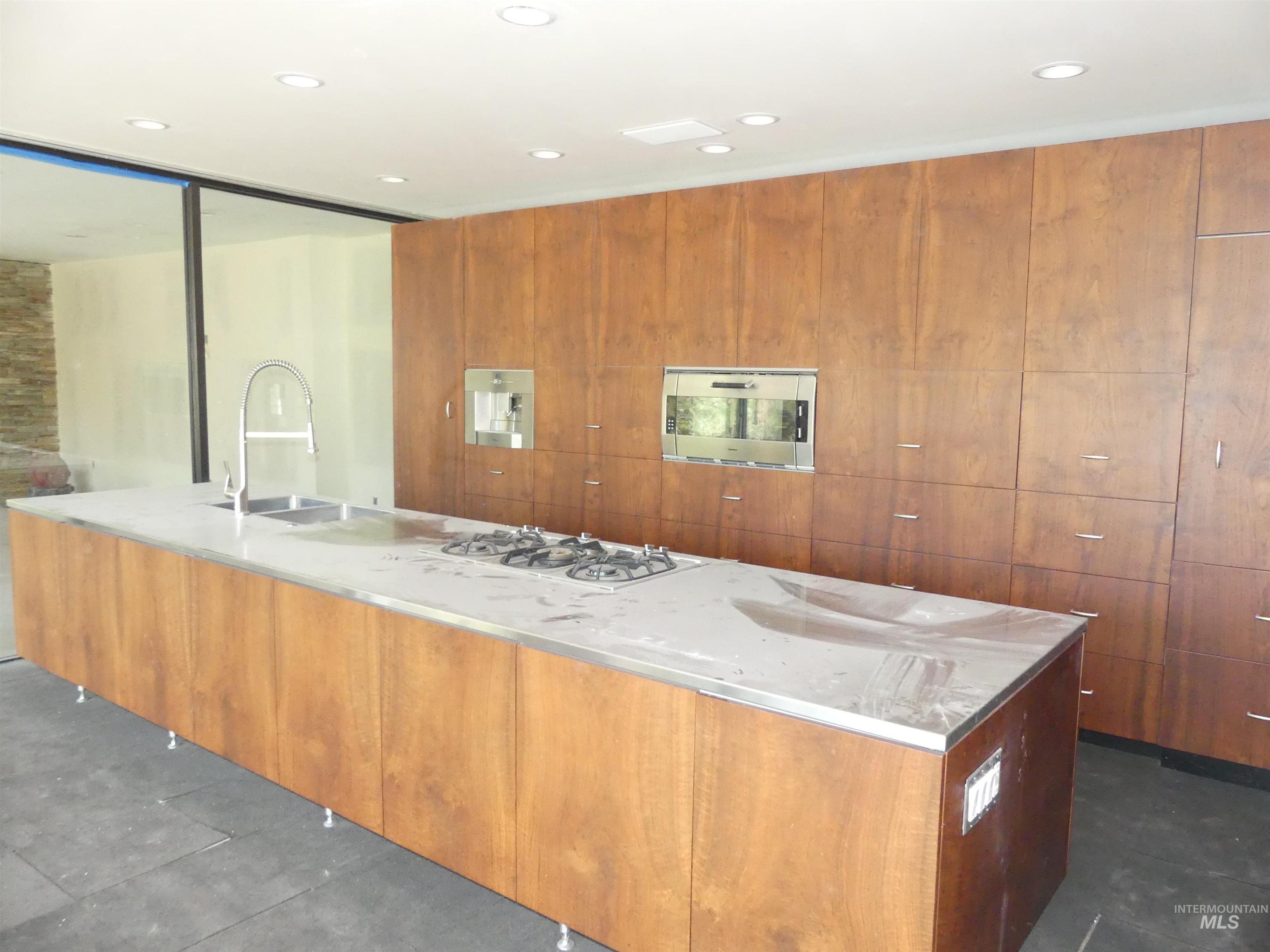 Kitchen with modern cabinets, brown cabinetry, a spacious island, and recessed lighting