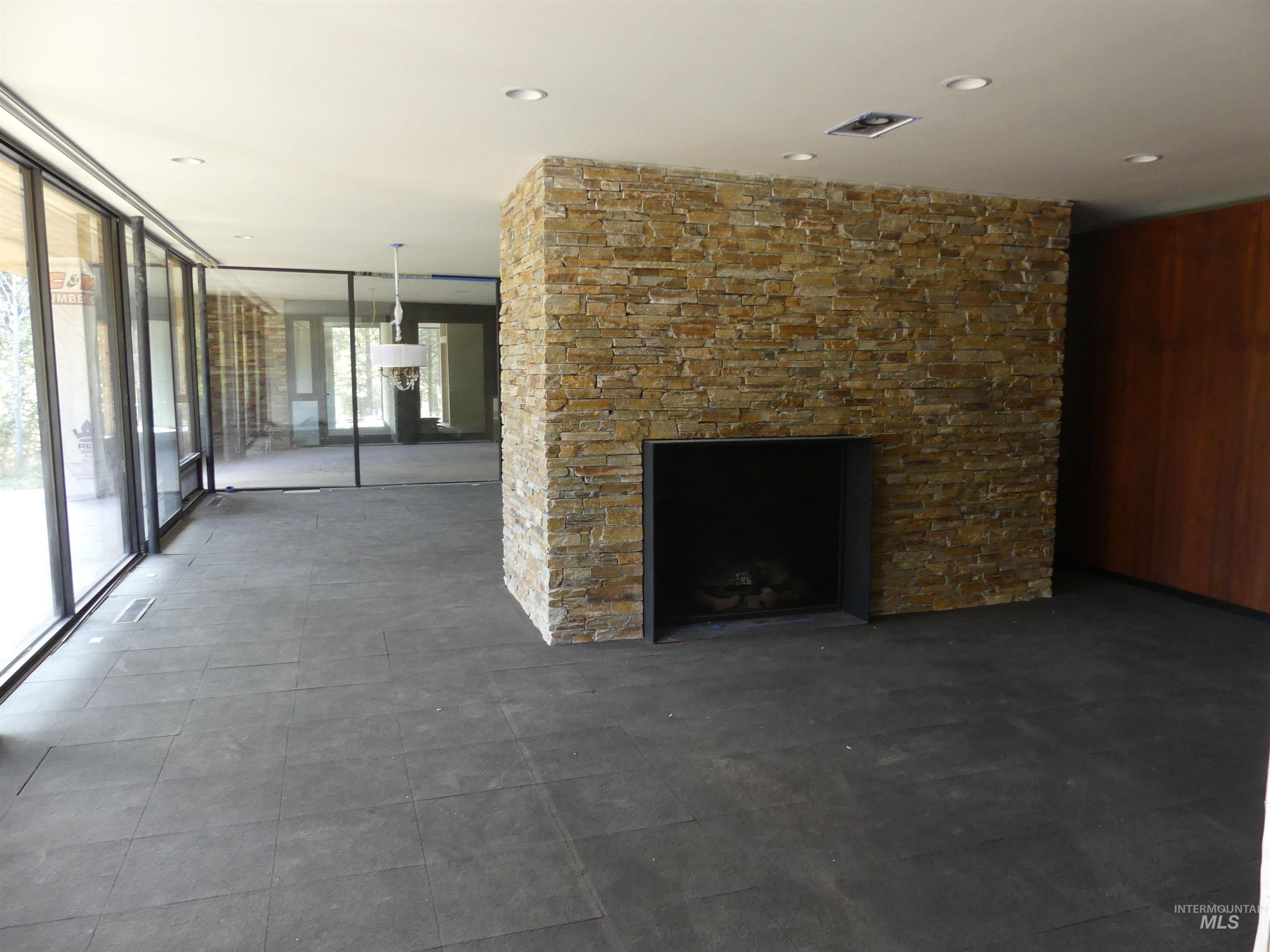 Unfurnished living room with expansive windows, a stone fireplace, and wood walls
