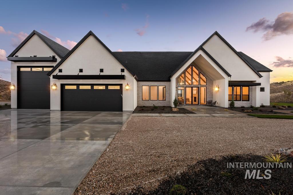 Modern farmhouse featuring a garage, concrete driveway, and stucco siding