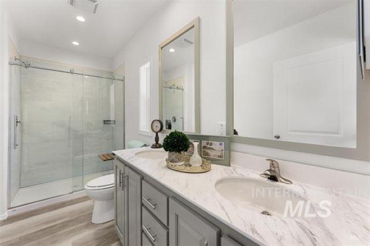 Bathroom with a stall shower, double vanity, light wood-style floors, and recessed lighting