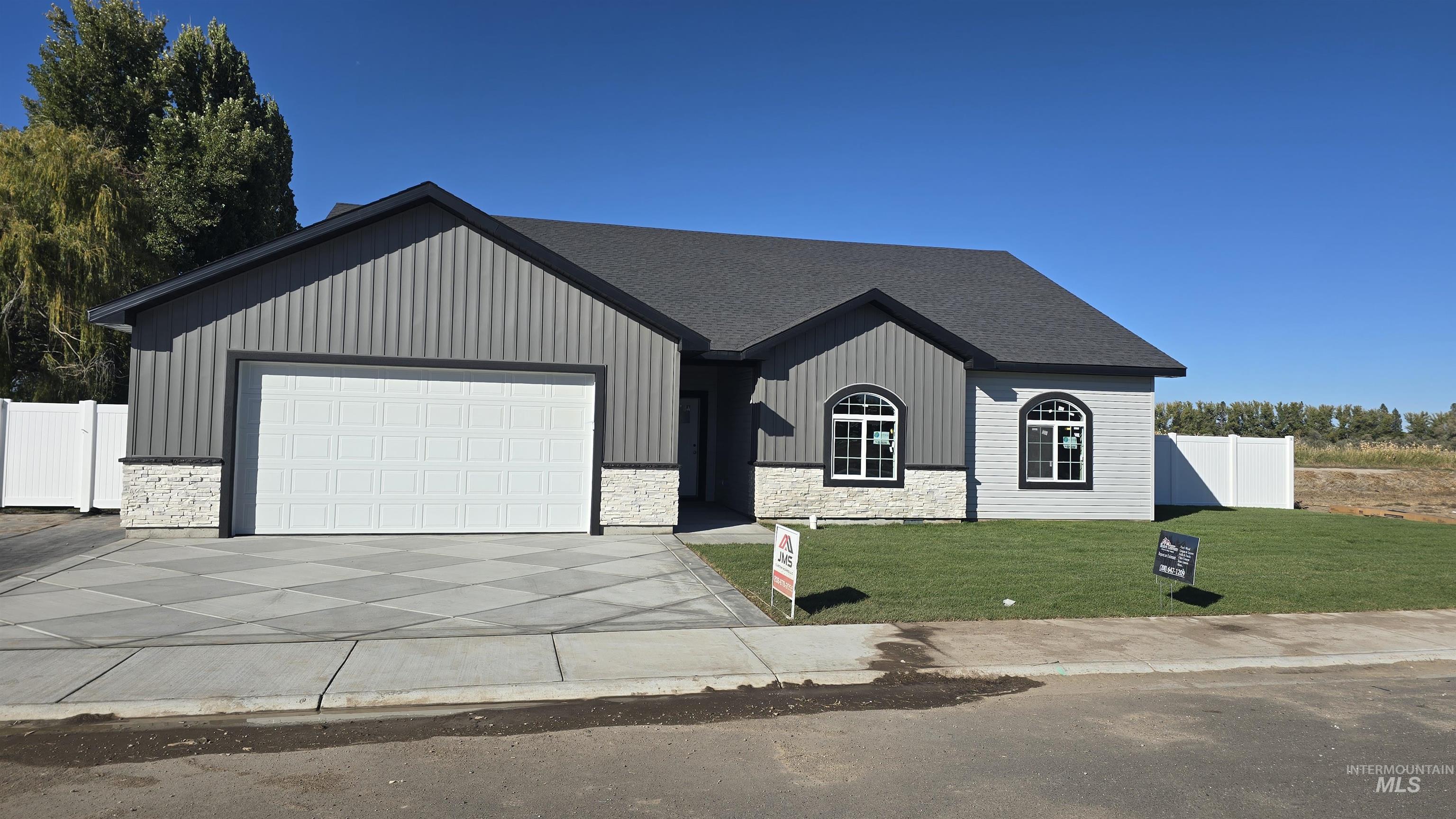 View of front of house featuring stone siding, driveway, an attached garage, and board and batten siding
