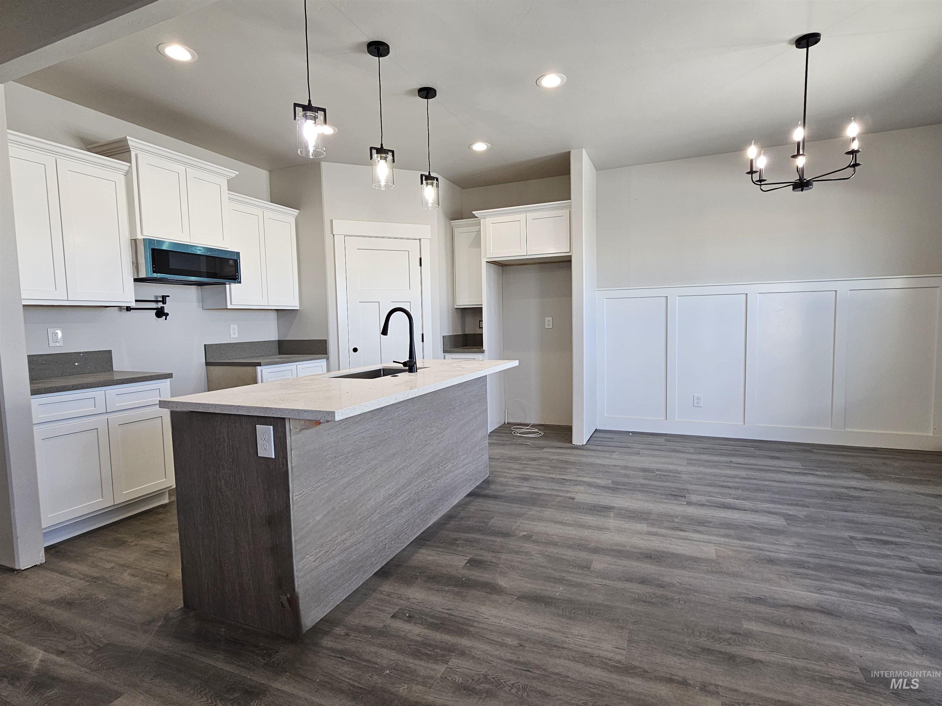 Kitchen with white cabinetry, a decorative wall, a center island with sink, dark wood-style flooring, and recessed lighting