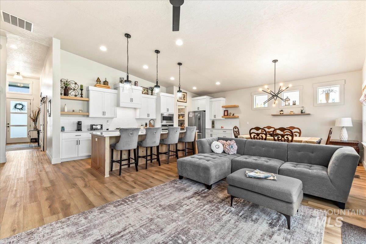 Living room with healthy amount of natural light, a chandelier, light wood finished floors, and recessed lighting