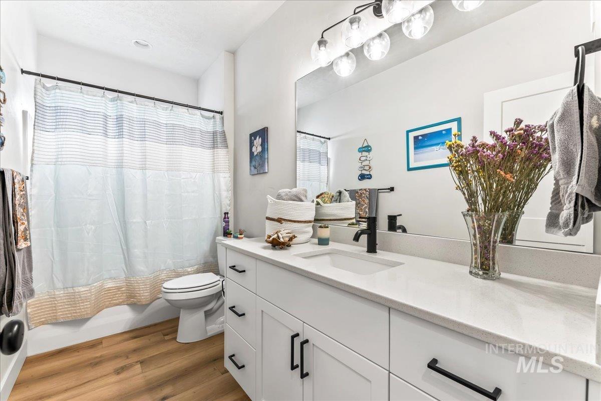 Bathroom with light wood-type flooring, vanity, and shower / bath combination with curtain