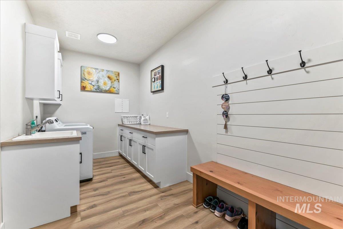 Washroom featuring light wood-style flooring, cabinet space, and washer and clothes dryer