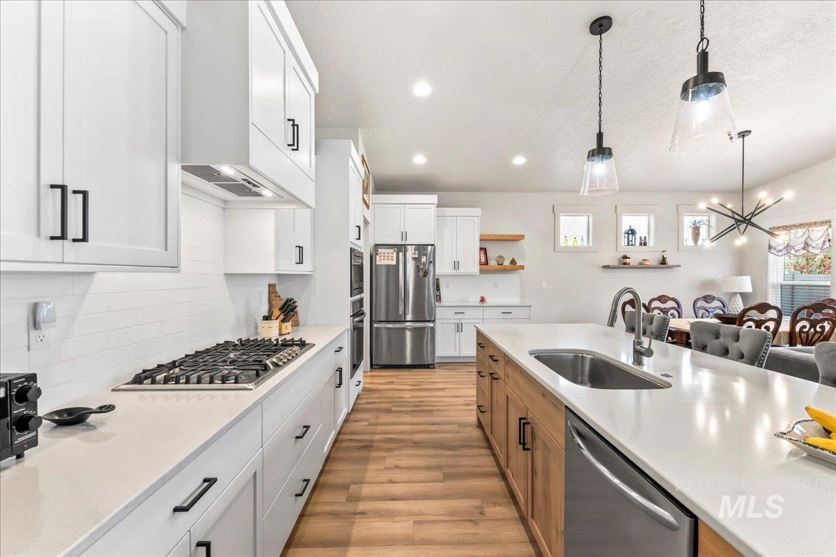 Kitchen featuring hanging light fixtures, white cabinets, a chandelier, appliances with stainless steel finishes, and open shelves