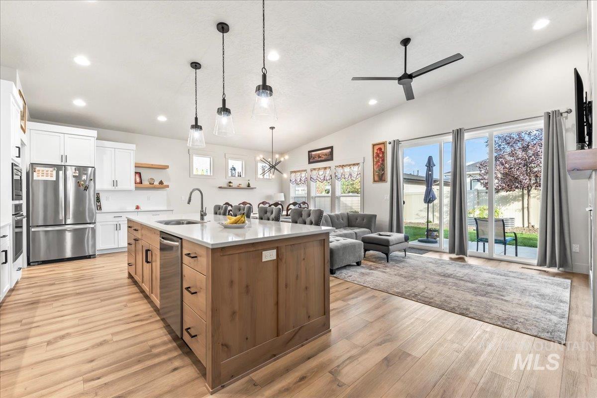 Kitchen with open floor plan, white cabinetry, stainless steel appliances, recessed lighting, and decorative light fixtures