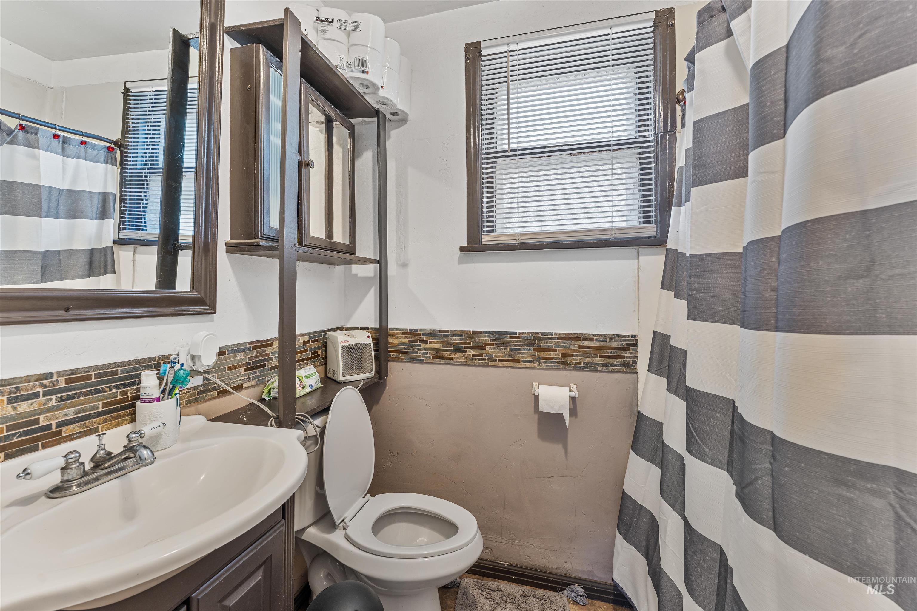 Bathroom featuring plenty of natural light, vanity, tile walls, wainscoting, and a shower with shower curtain