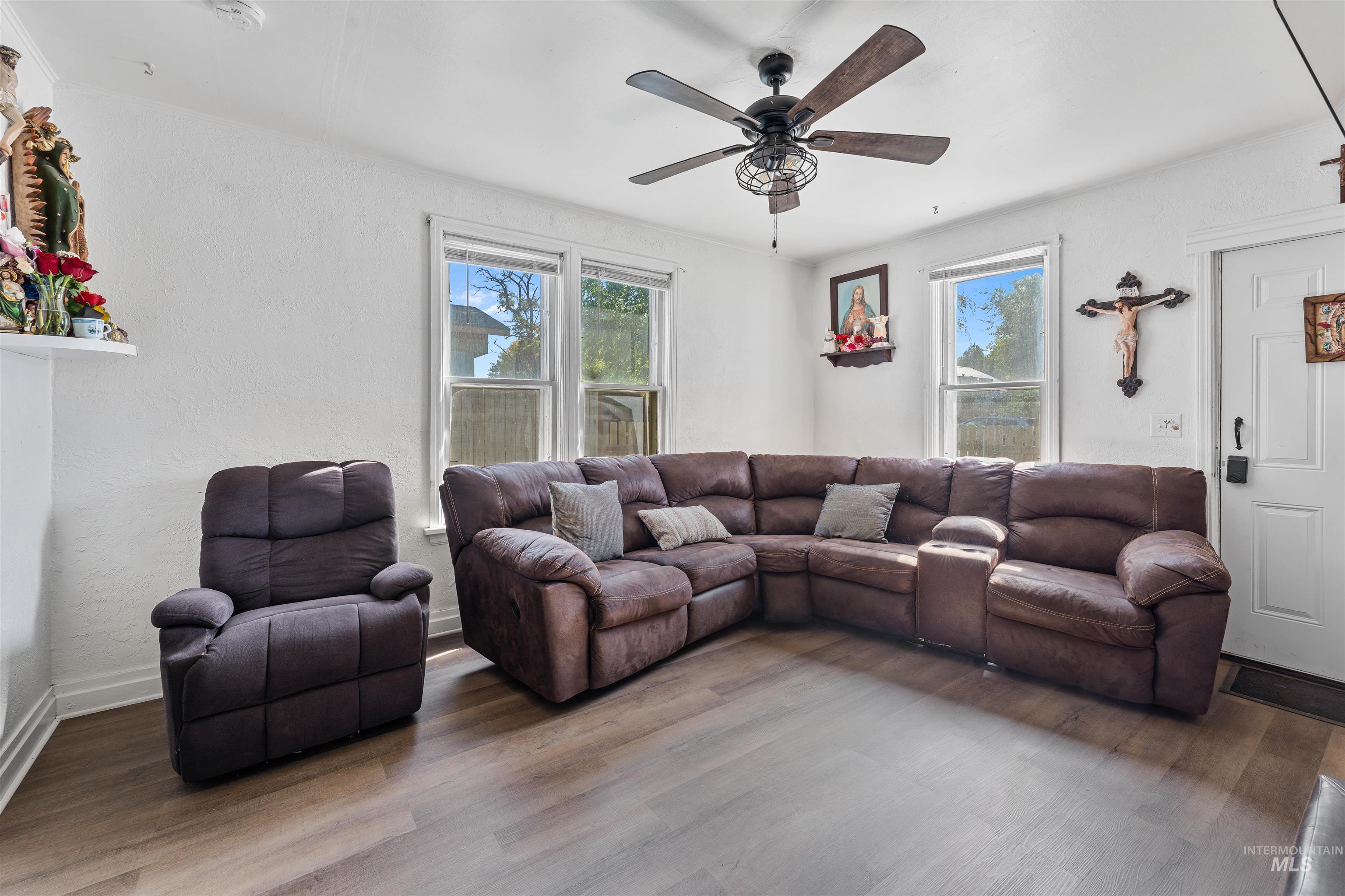 Living room featuring wood finished floors, healthy amount of natural light, a ceiling fan, and a textured wall
