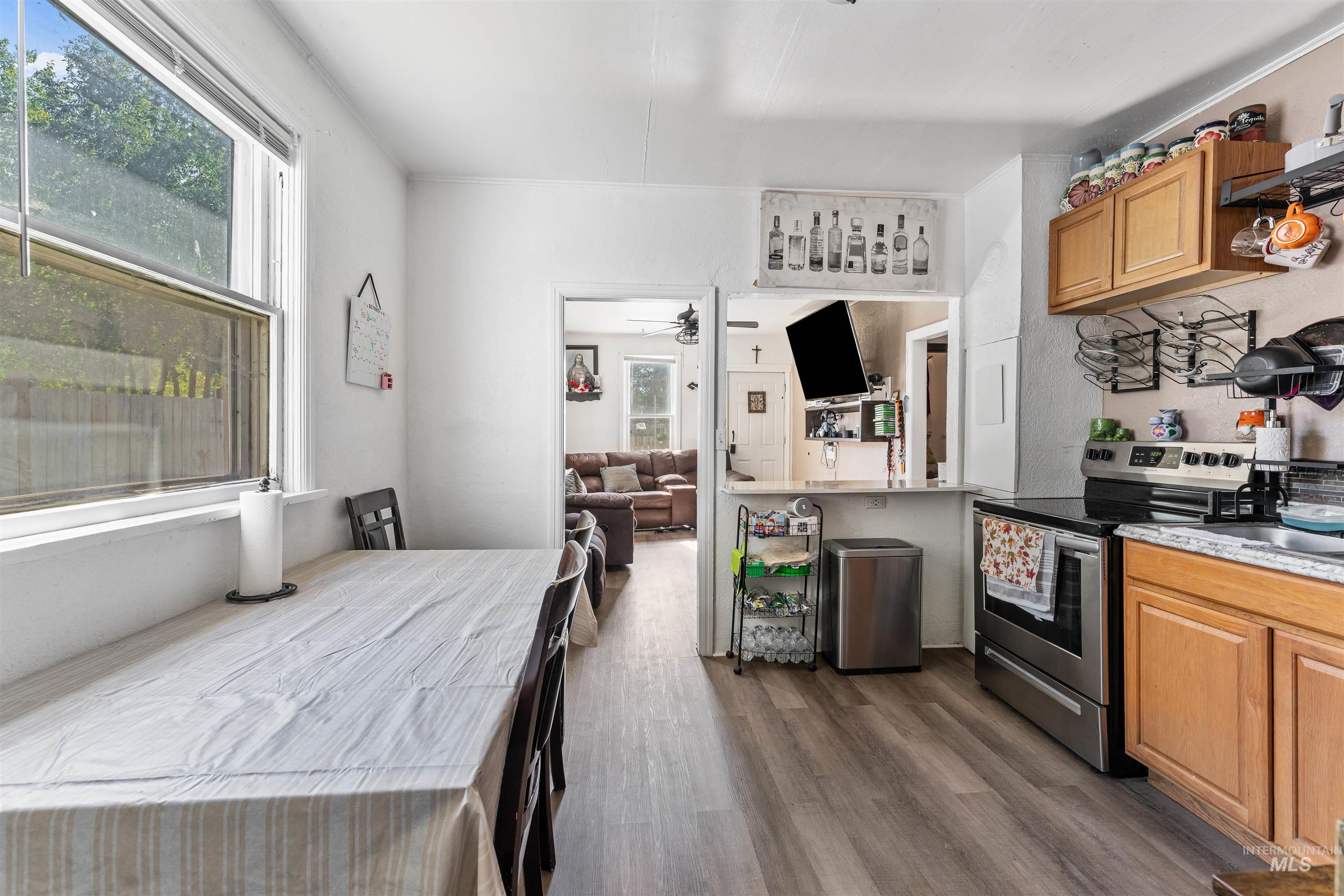 Kitchen featuring open floor plan, stainless steel electric range oven, brown cabinetry, and healthy amount of natural light