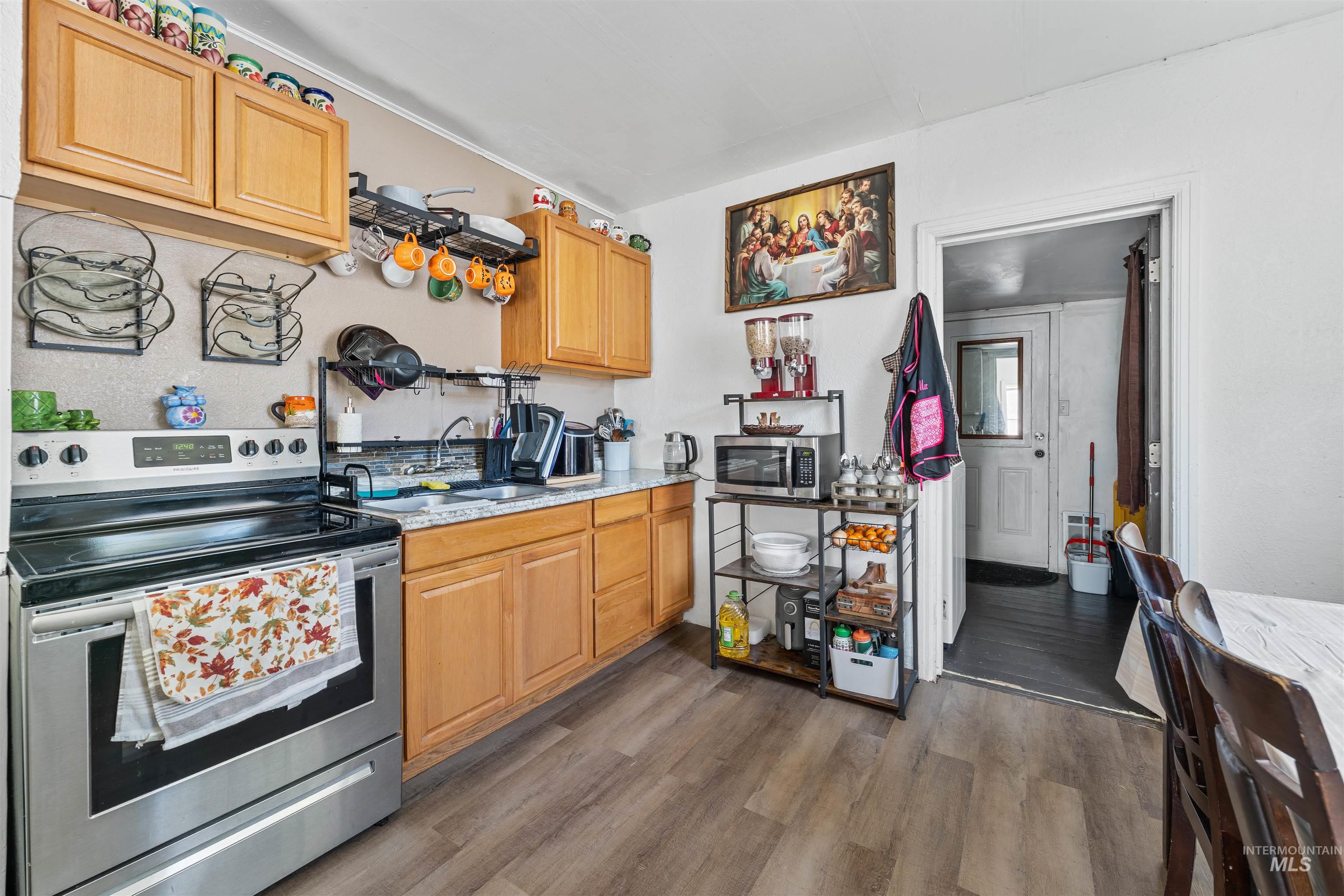 Kitchen with appliances with stainless steel finishes, dark wood-type flooring, and light stone counters