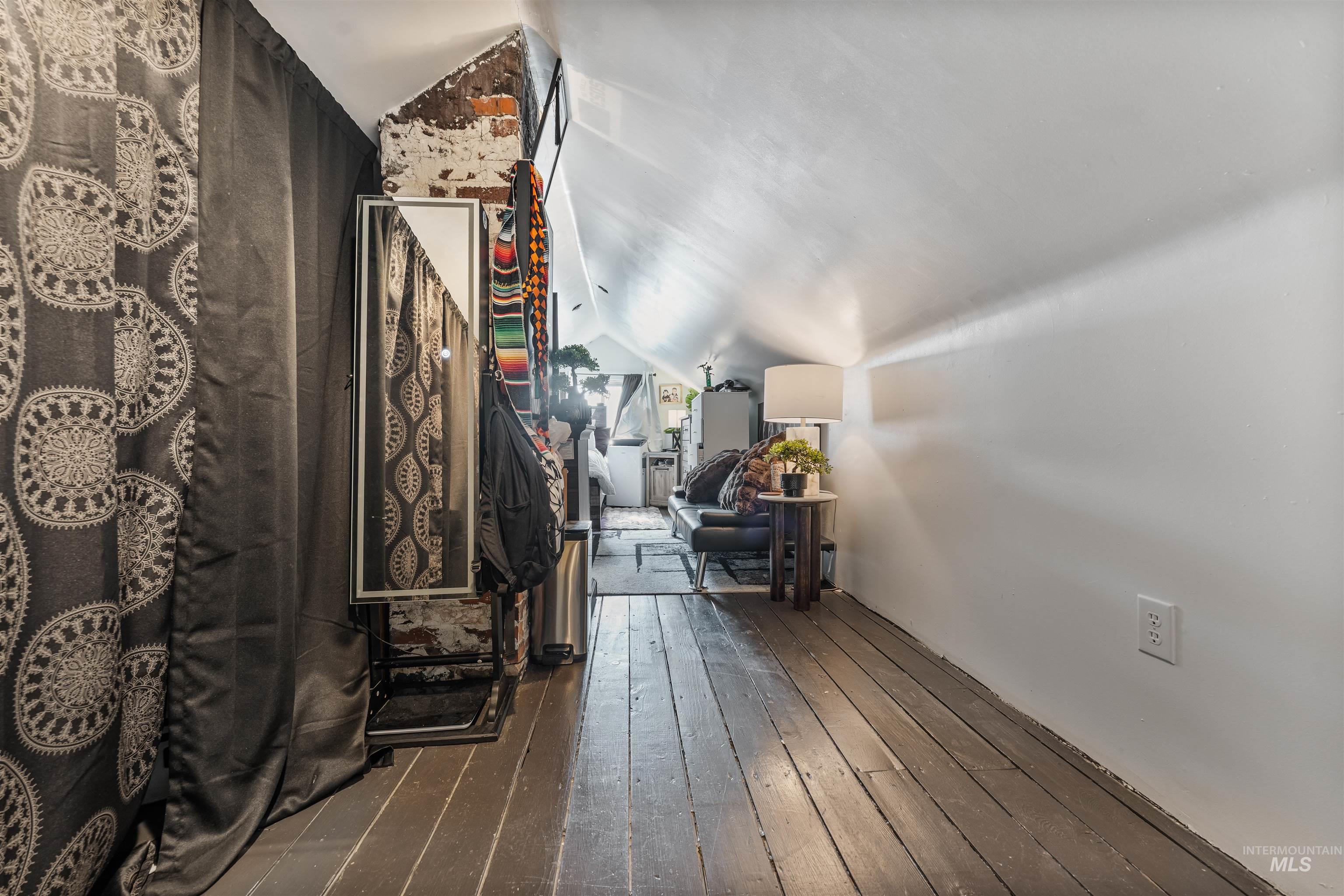Corridor featuring vaulted ceiling and dark wood-style flooring