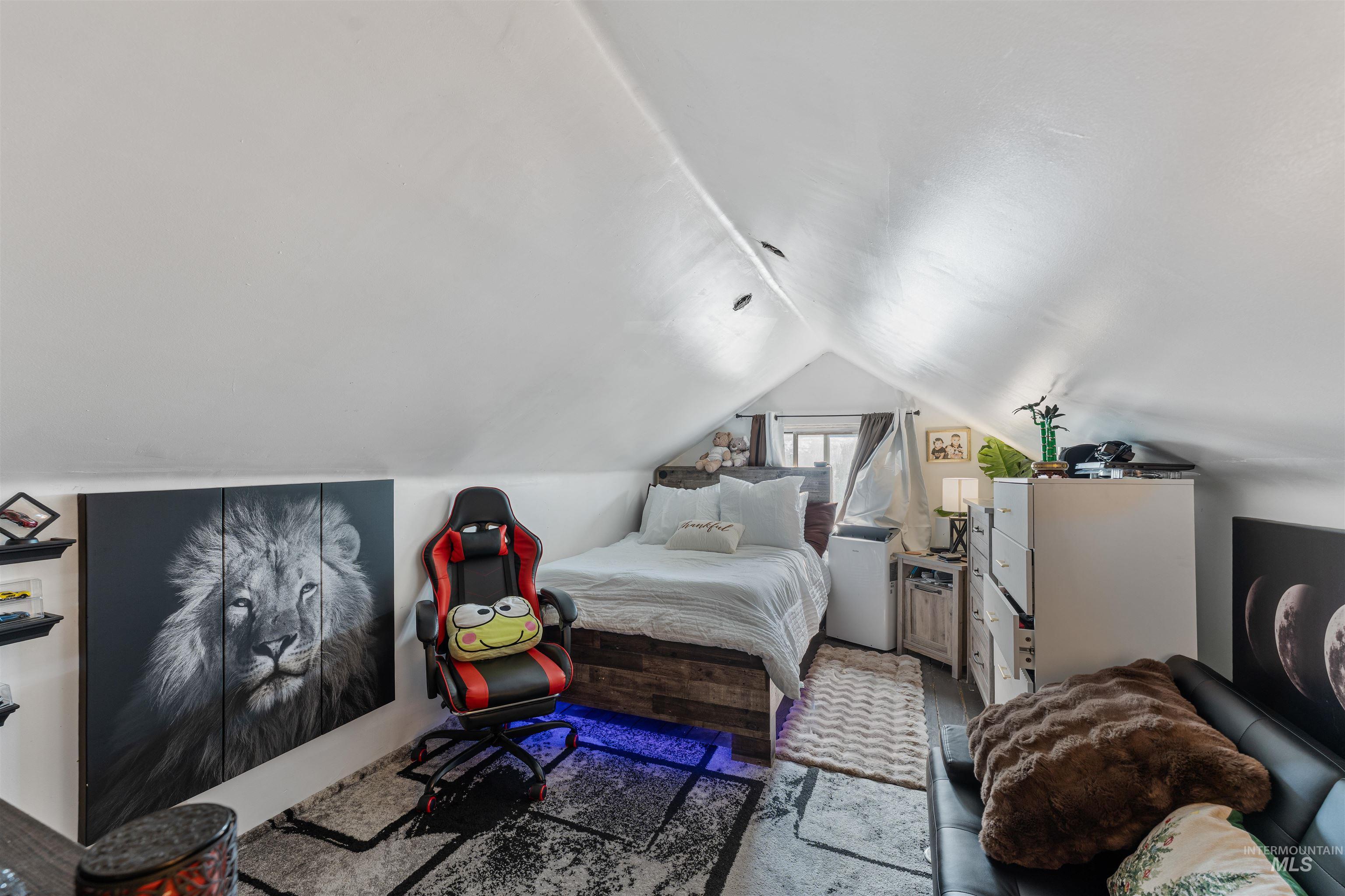 Bedroom with vaulted ceiling, wood finished floors, and white refrigerator