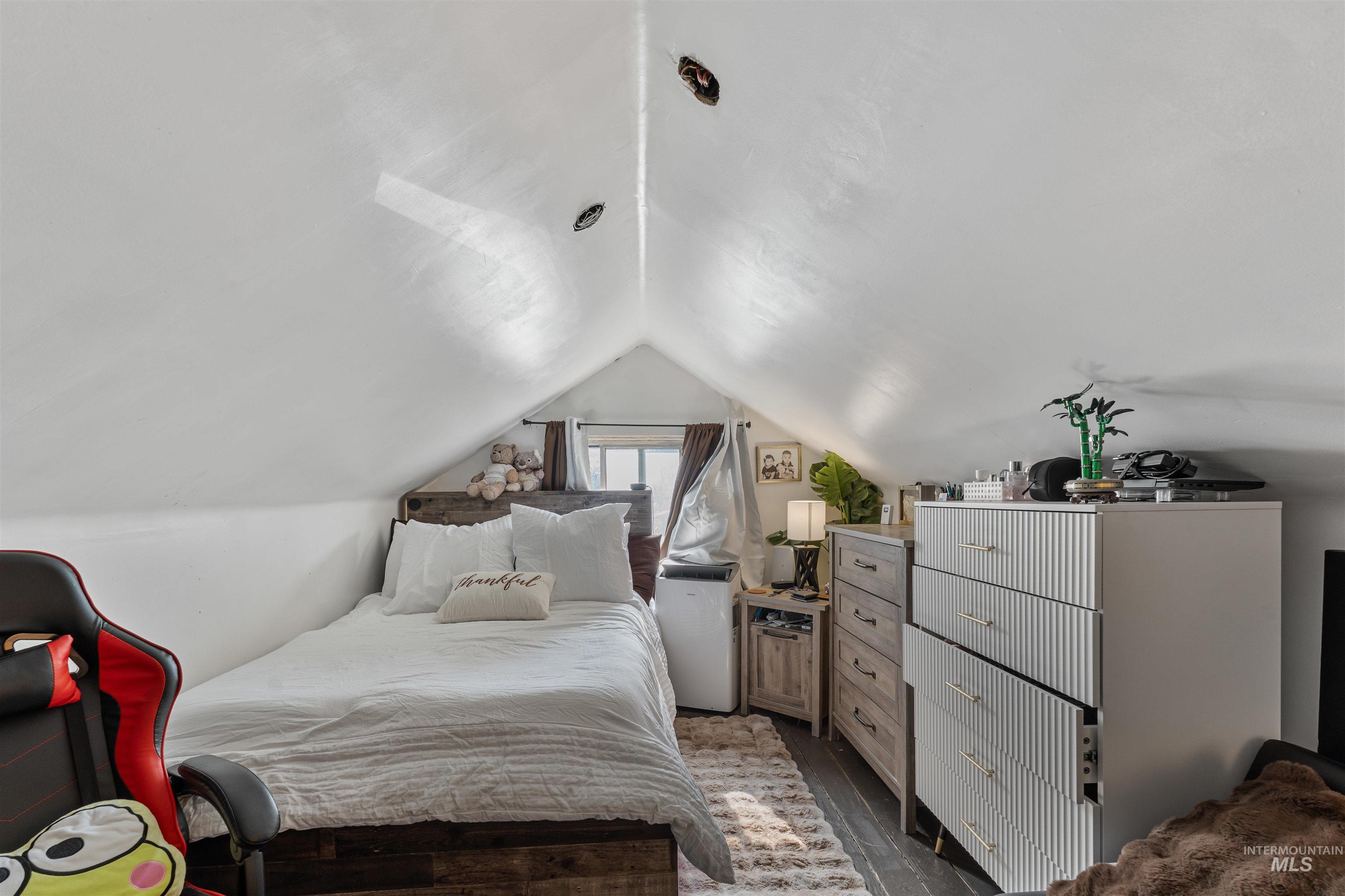 Bedroom featuring dark wood finished floors and lofted ceiling