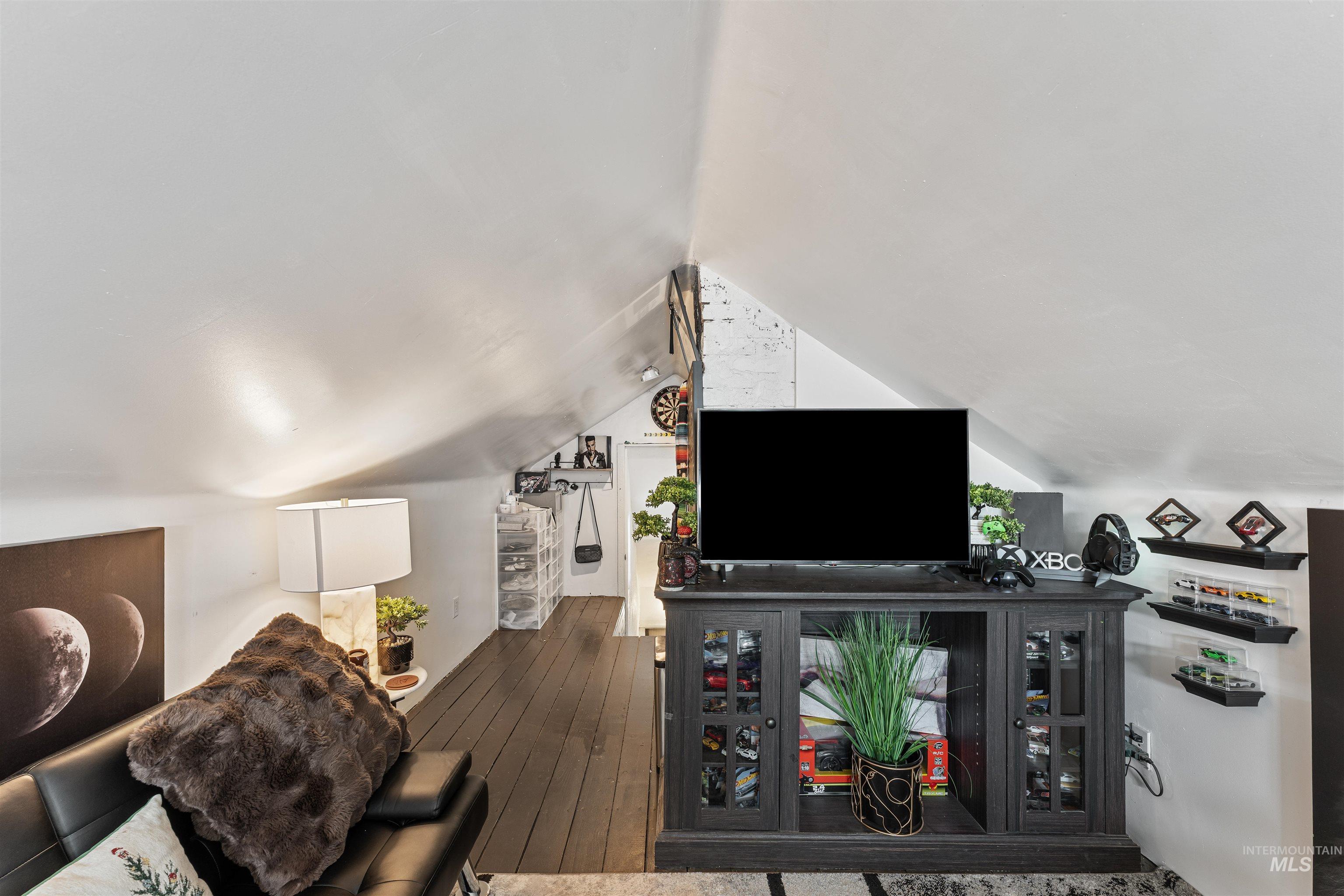 Living room featuring dark wood-style floors and vaulted ceiling