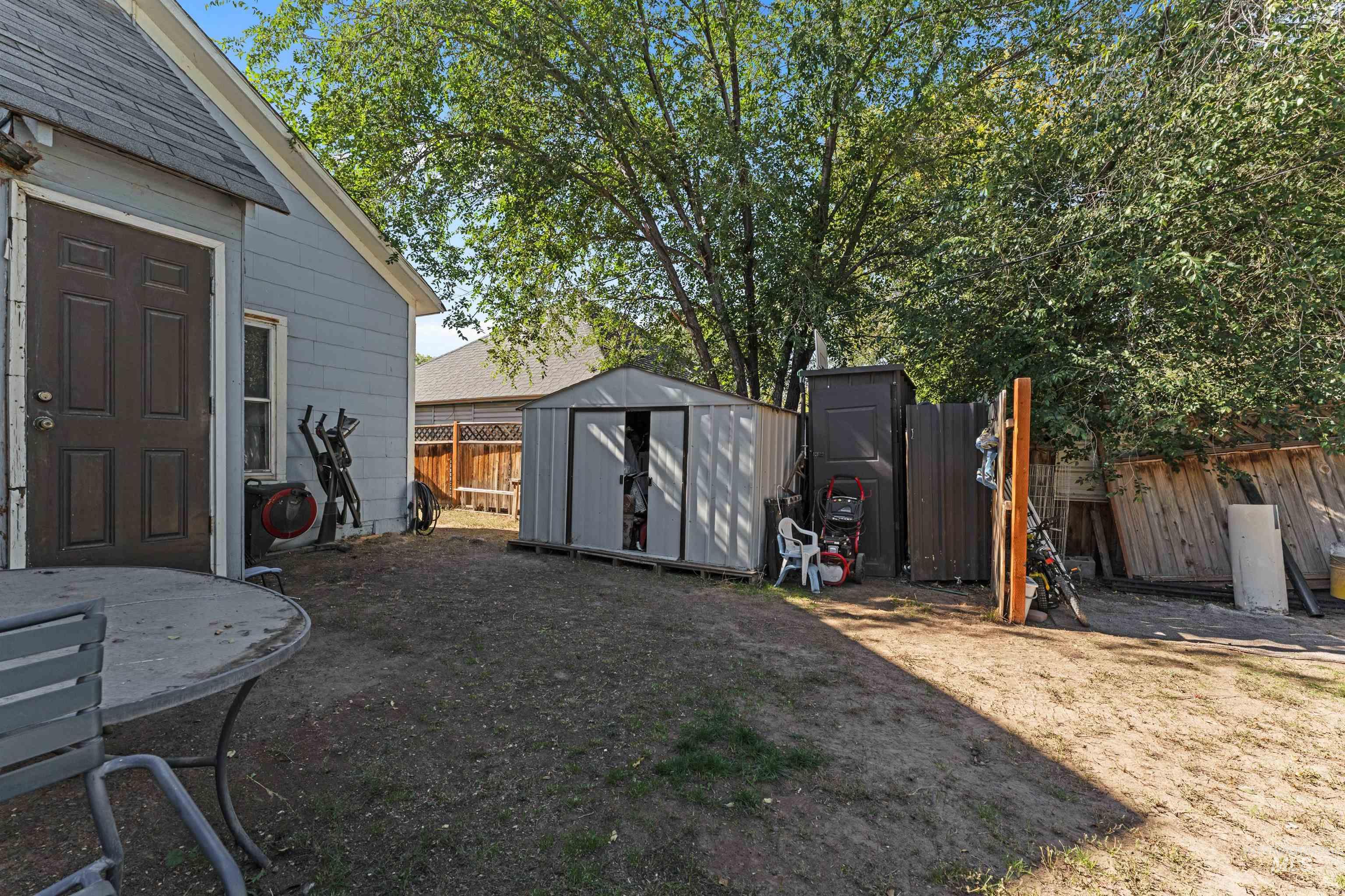 Fenced backyard with a storage unit and a patio