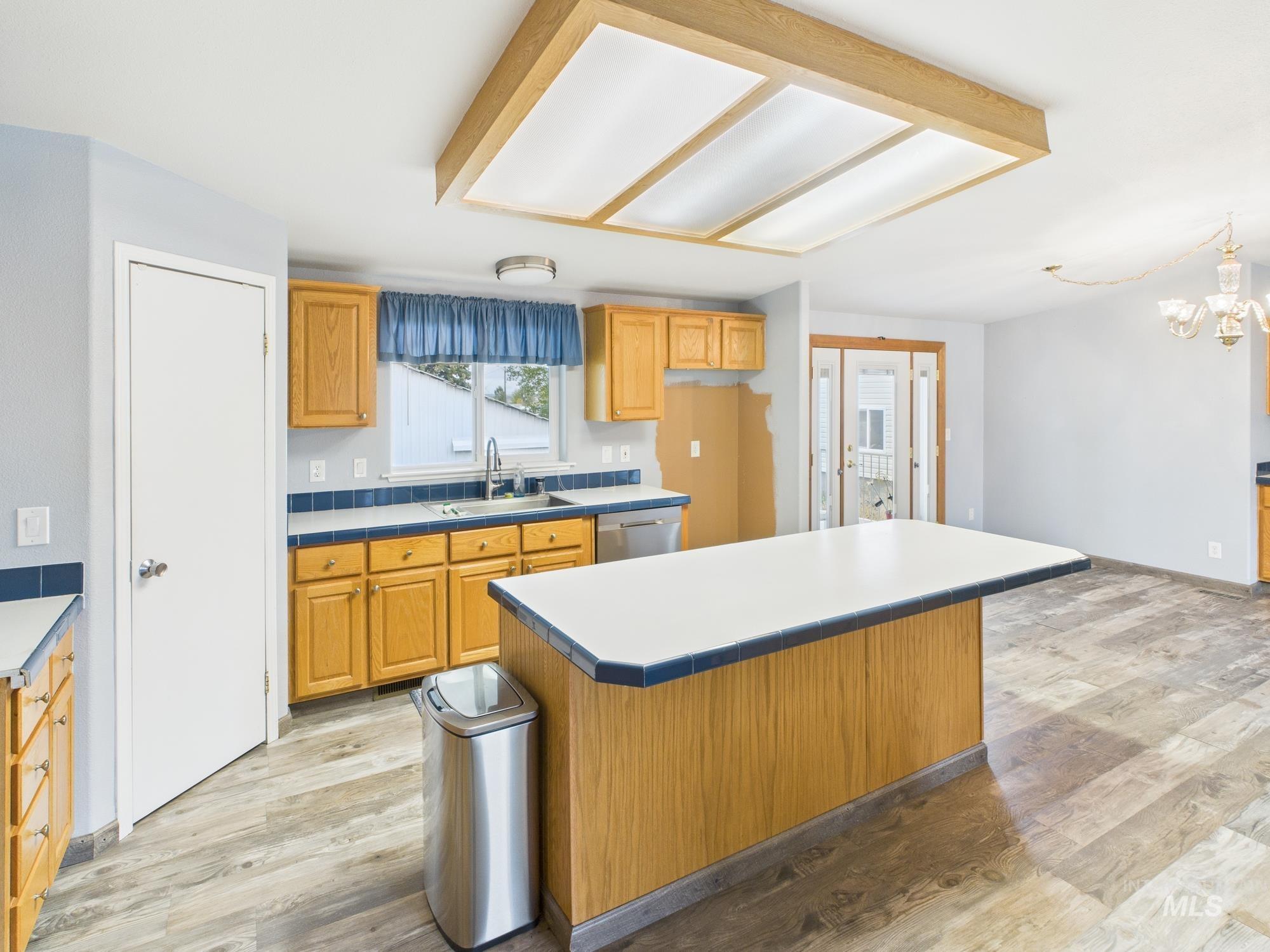 Kitchen with light wood-type flooring, light countertops, a center island, and brown cabinets