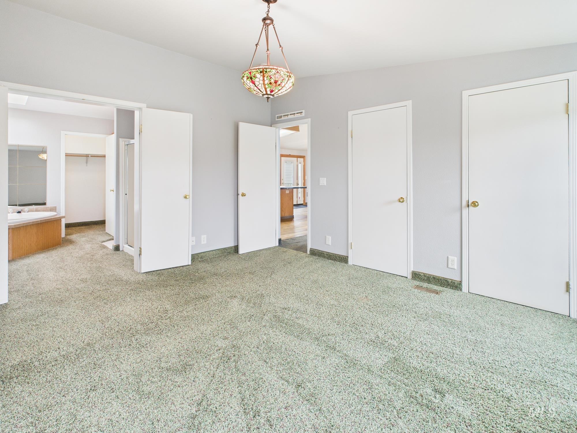 Unfurnished bedroom featuring light colored carpet and multiple closets