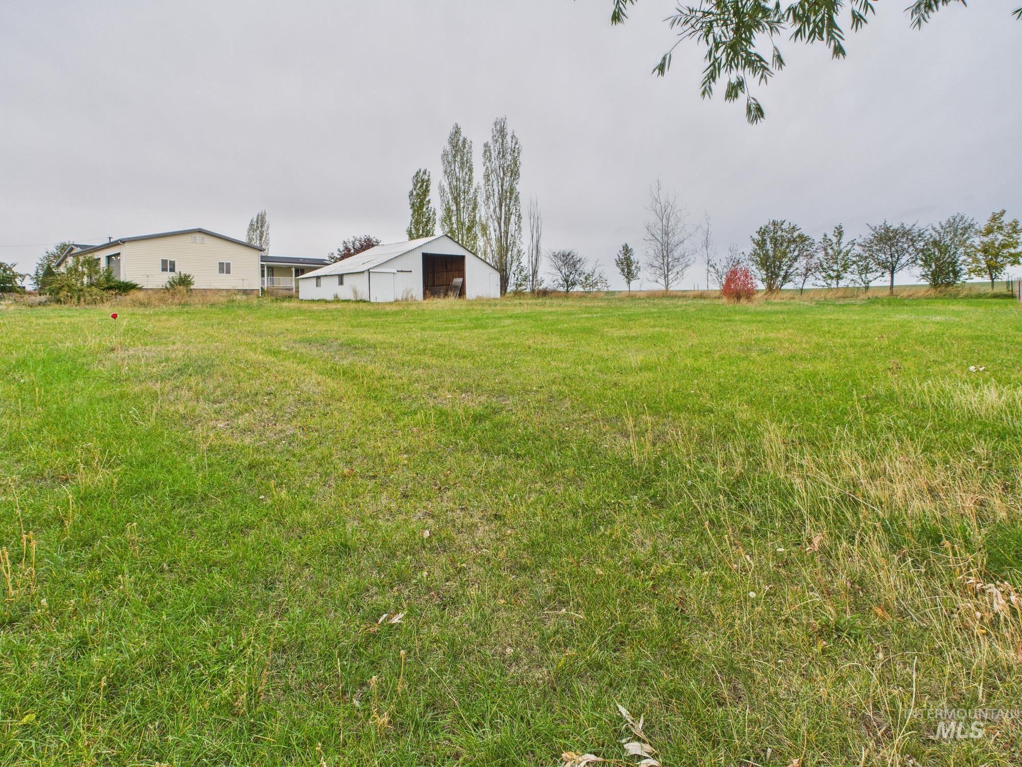 View of green lawn with a pole building and an outbuilding