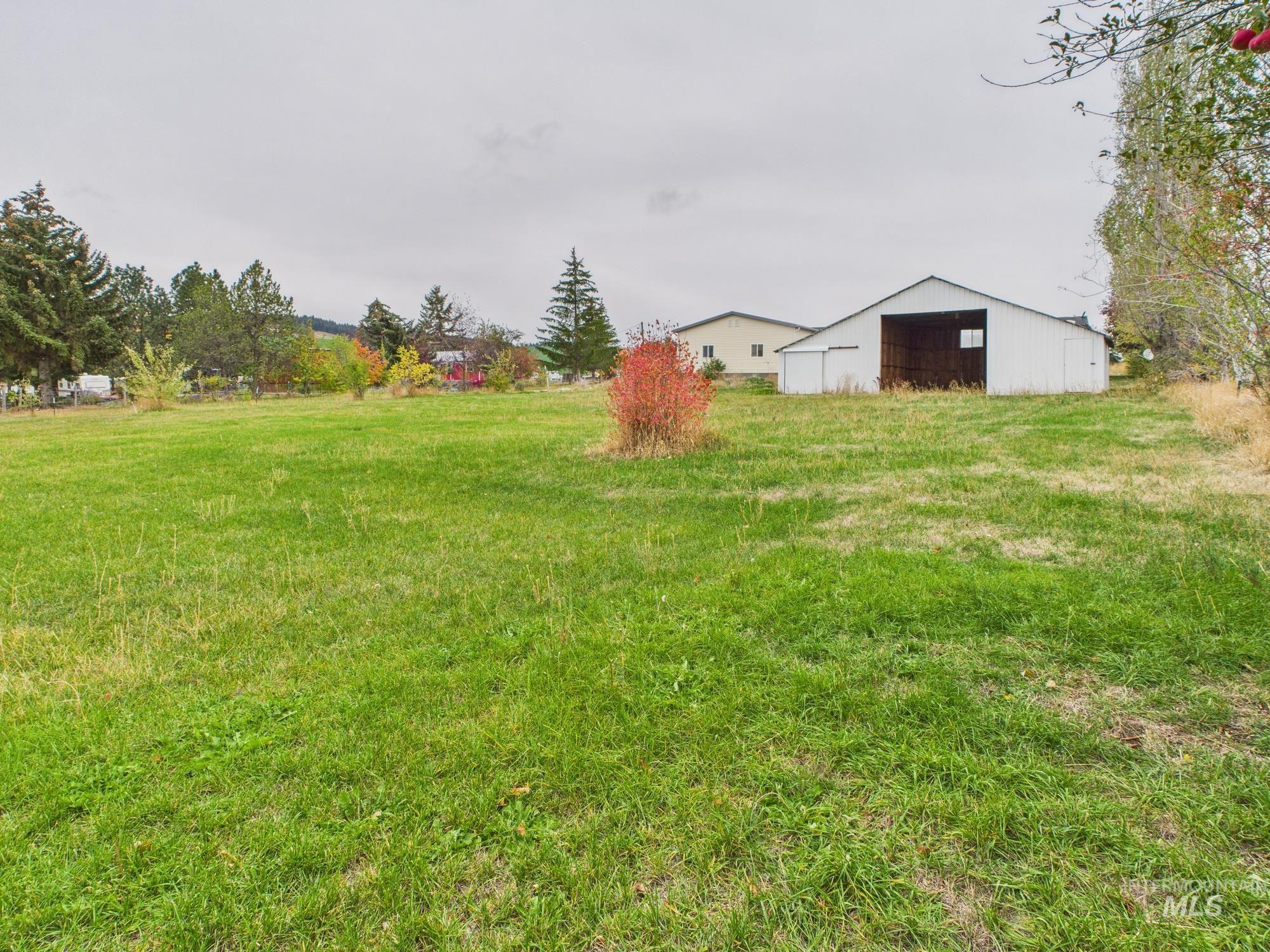 View of grassy yard featuring an outbuilding, an outdoor structure, and a detached garage