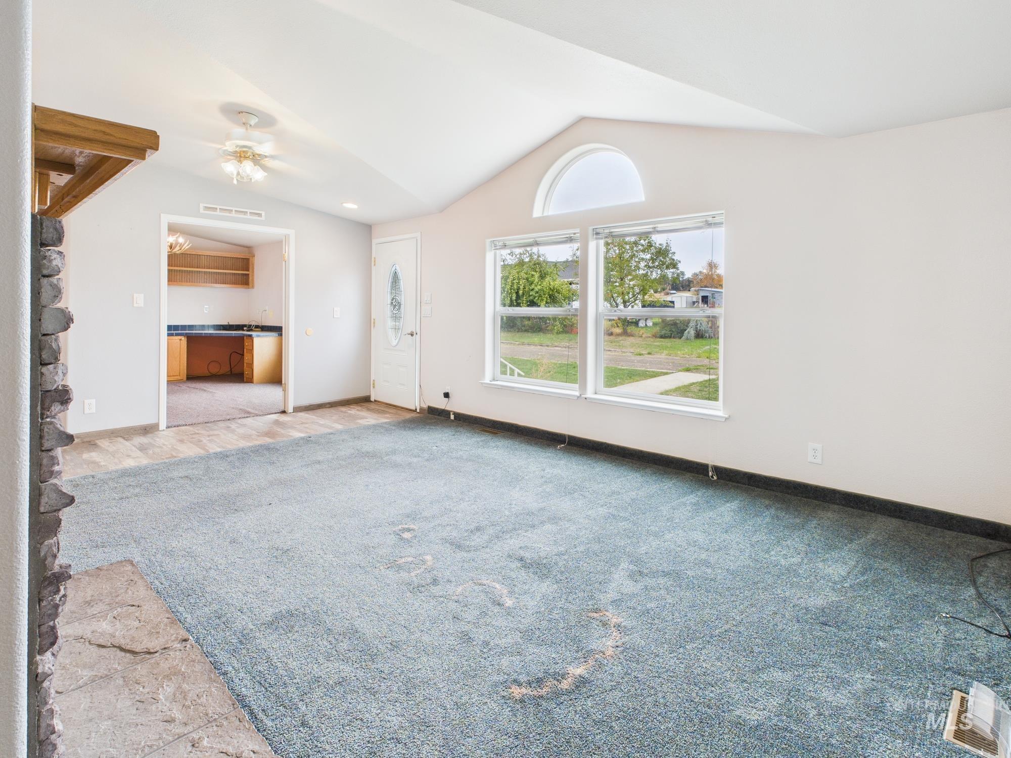 Unfurnished living room with vaulted ceiling, light colored carpet, and ceiling fan