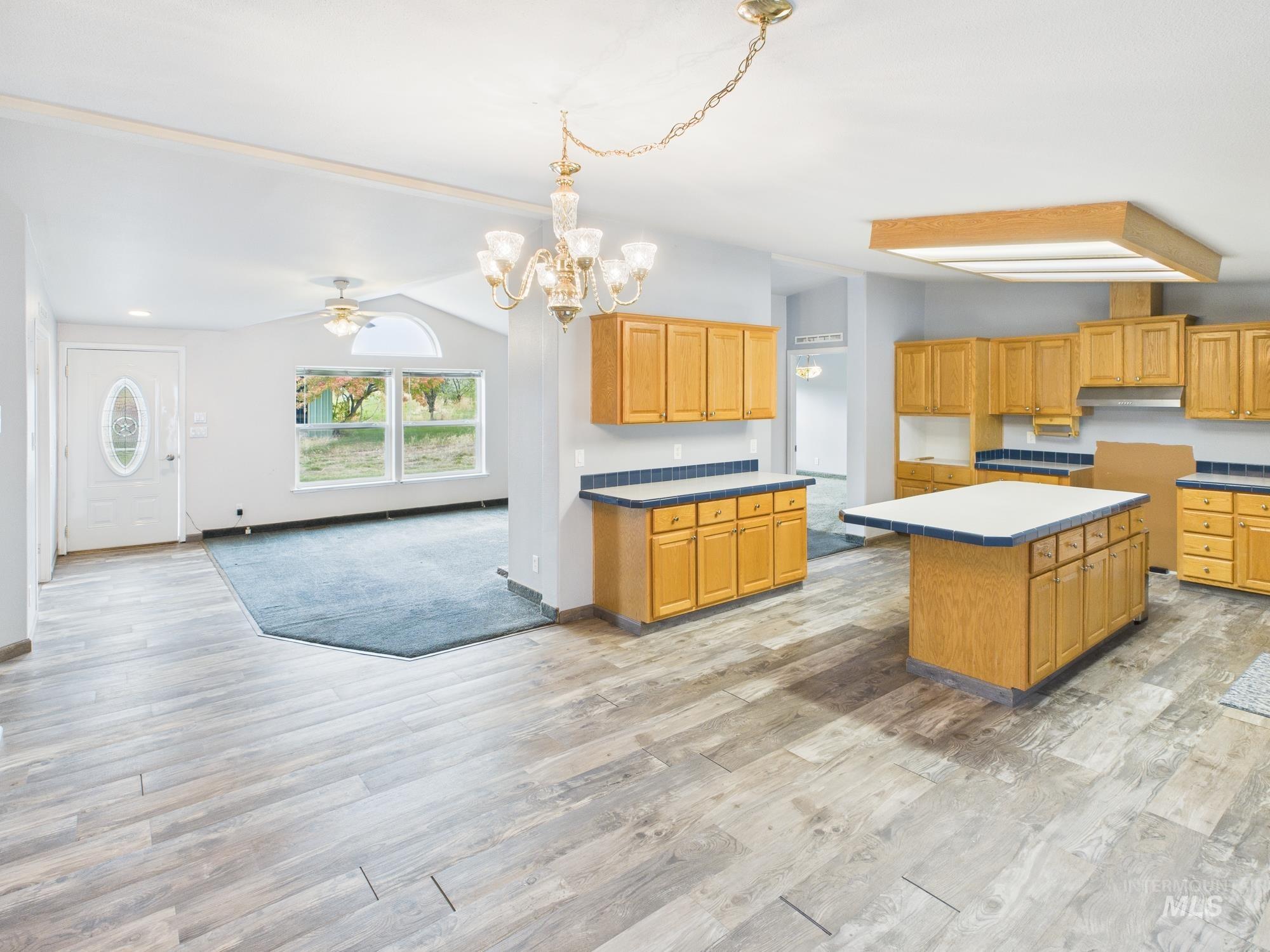Kitchen with open floor plan, a ceiling fan, light wood-style flooring, and a kitchen island