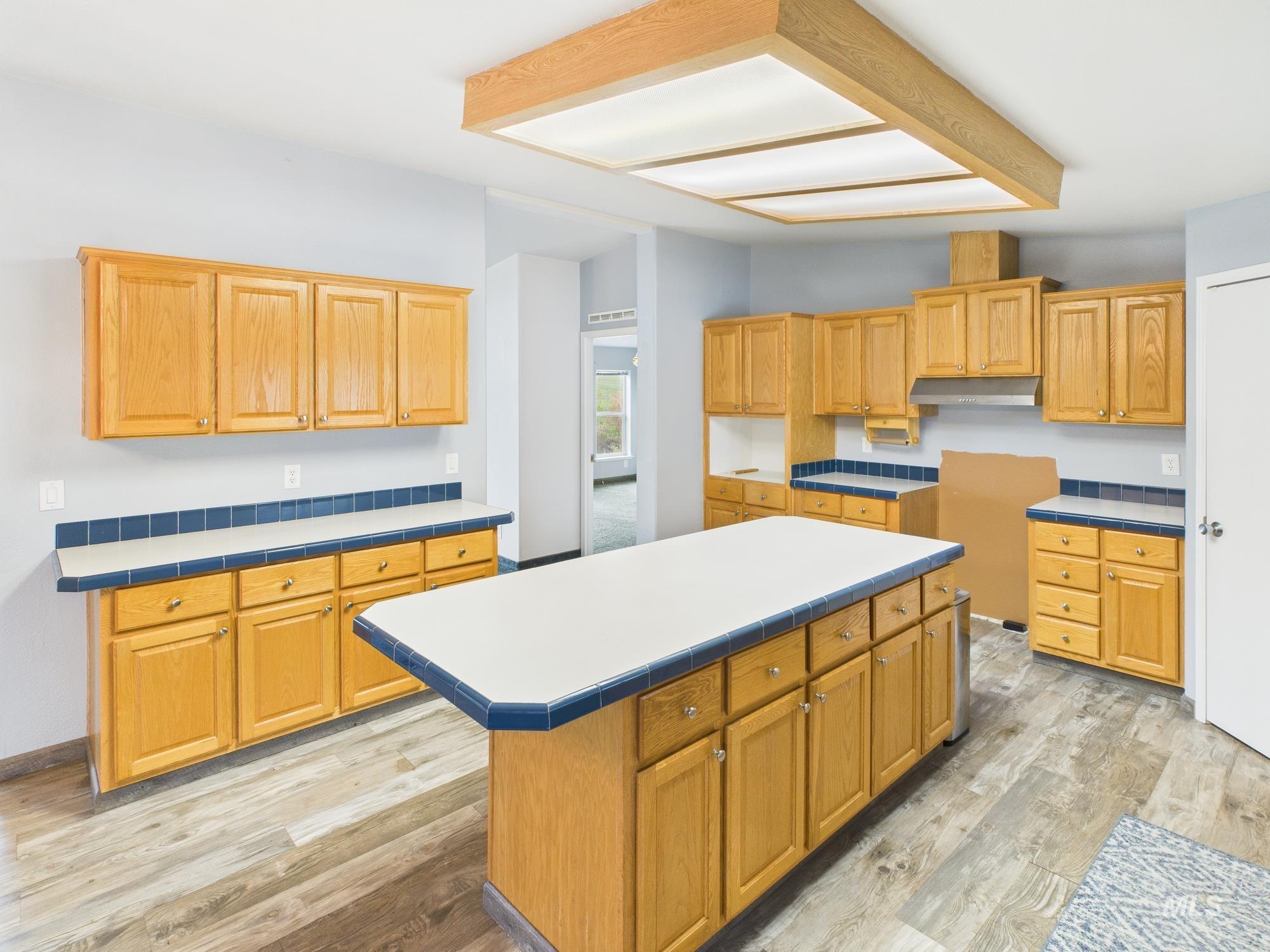 Kitchen with a center island, light wood-type flooring, light countertops, and under cabinet range hood
