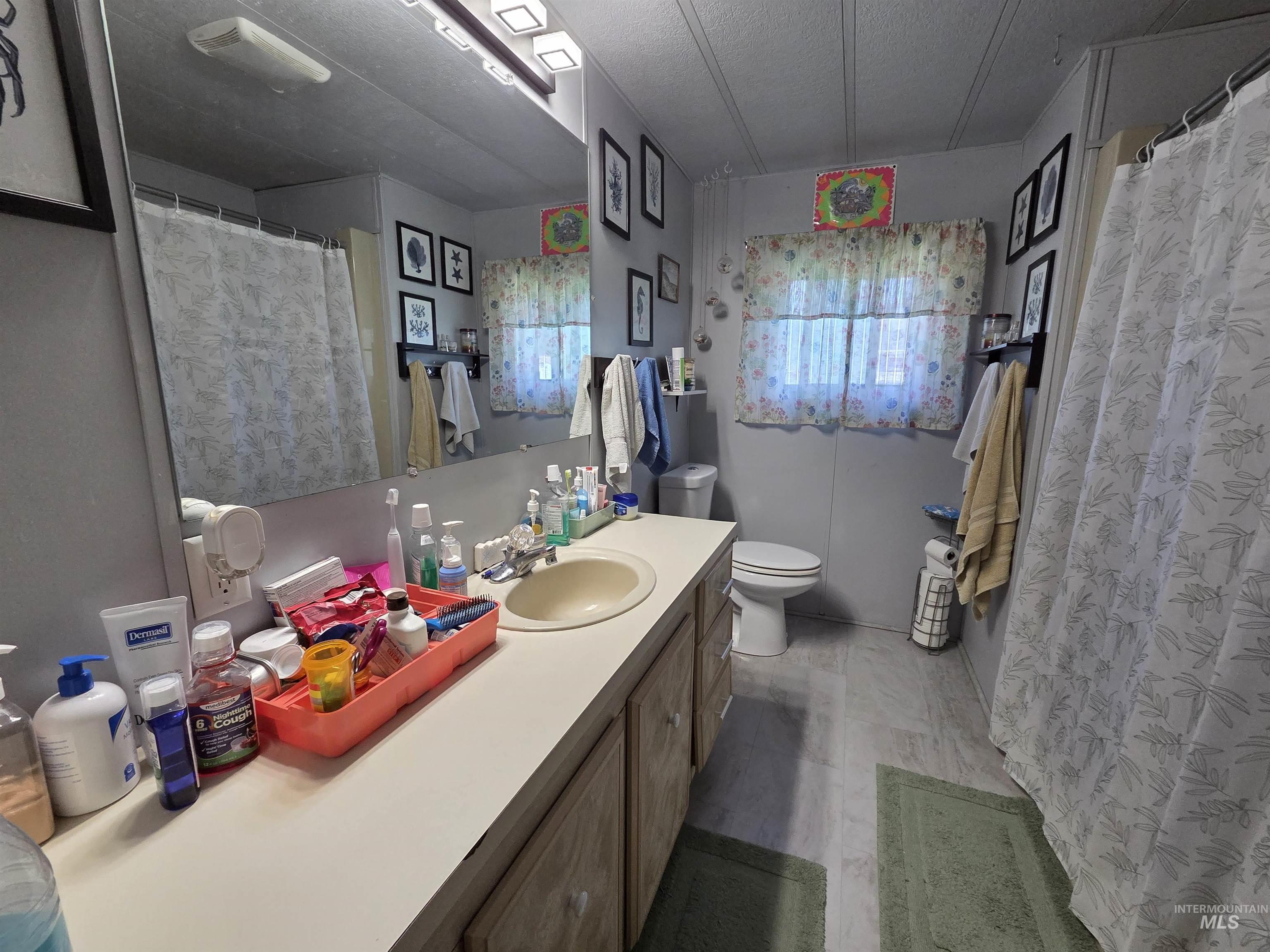Bathroom featuring vanity, a textured ceiling, and curtained shower