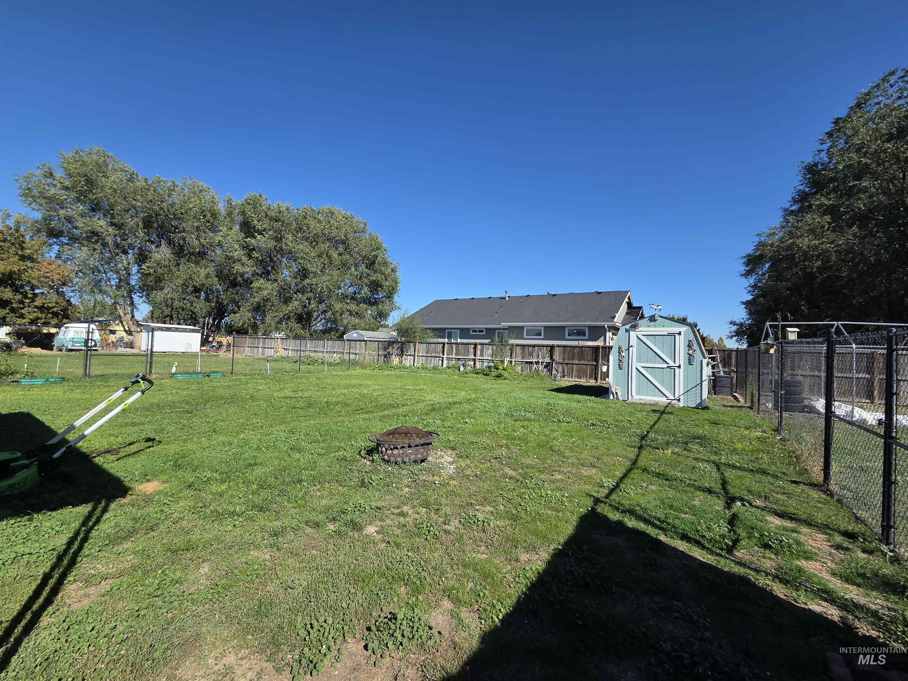 Fenced backyard featuring an outdoor fire pit and a shed