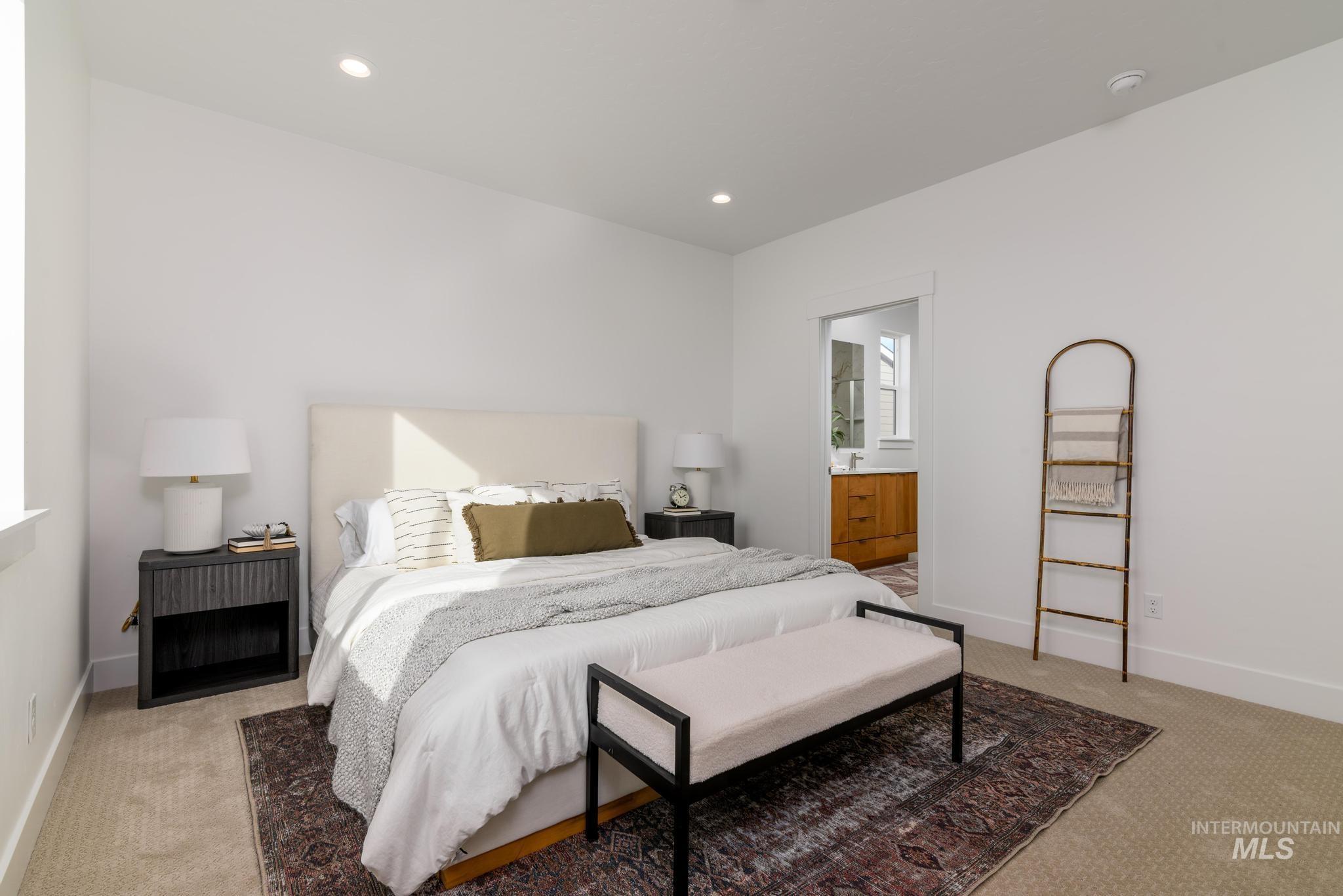 Bedroom with light colored carpet, recessed lighting, and ensuite bath