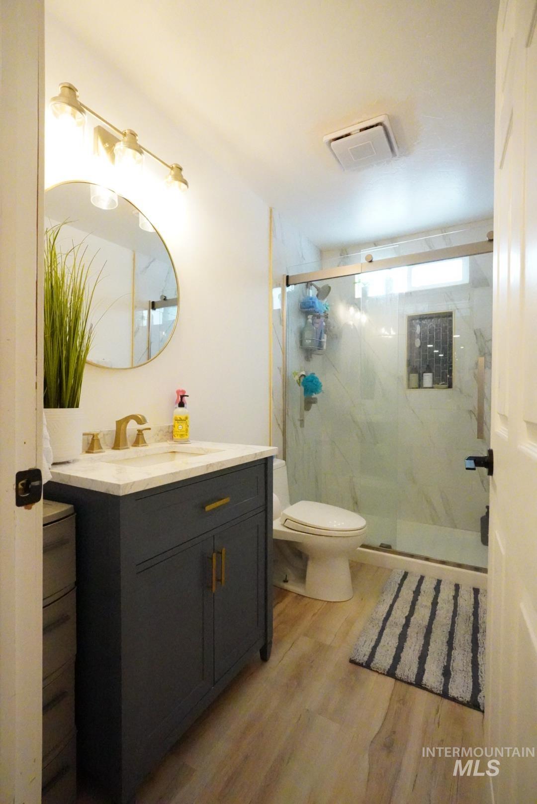 Full bathroom with vanity, a marble finish shower, and light wood-style flooring