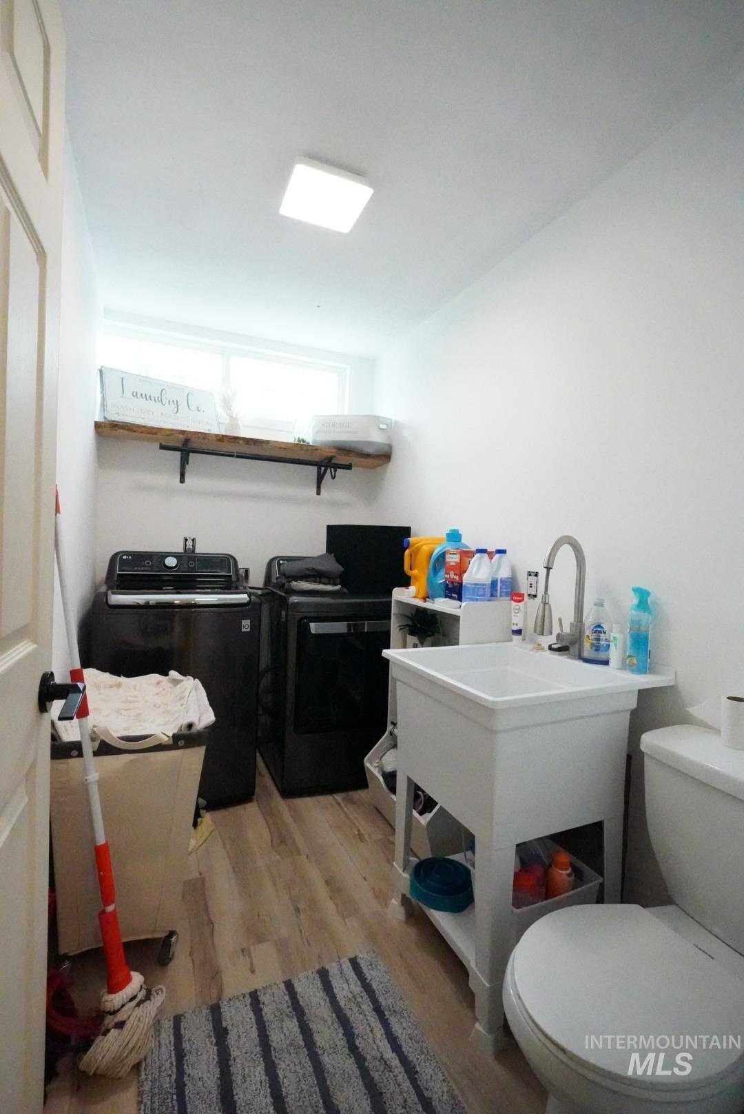 Washroom featuring light wood-type flooring and washing machine and clothes dryer