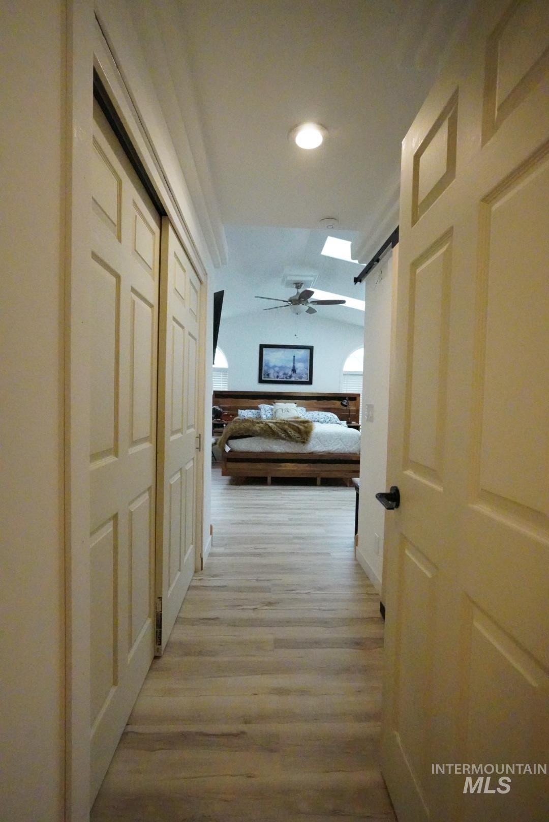 Hallway with lofted ceiling, light wood-style floors, a barn door, and recessed lighting