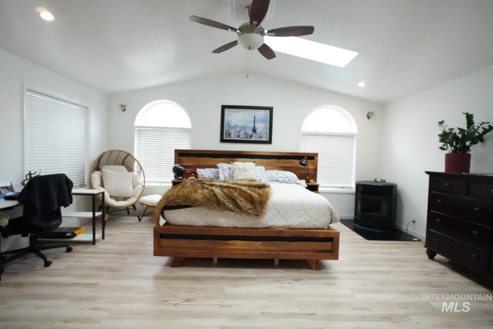 Bedroom featuring light wood-style flooring, recessed lighting, lofted ceiling, a skylight, and ceiling fan