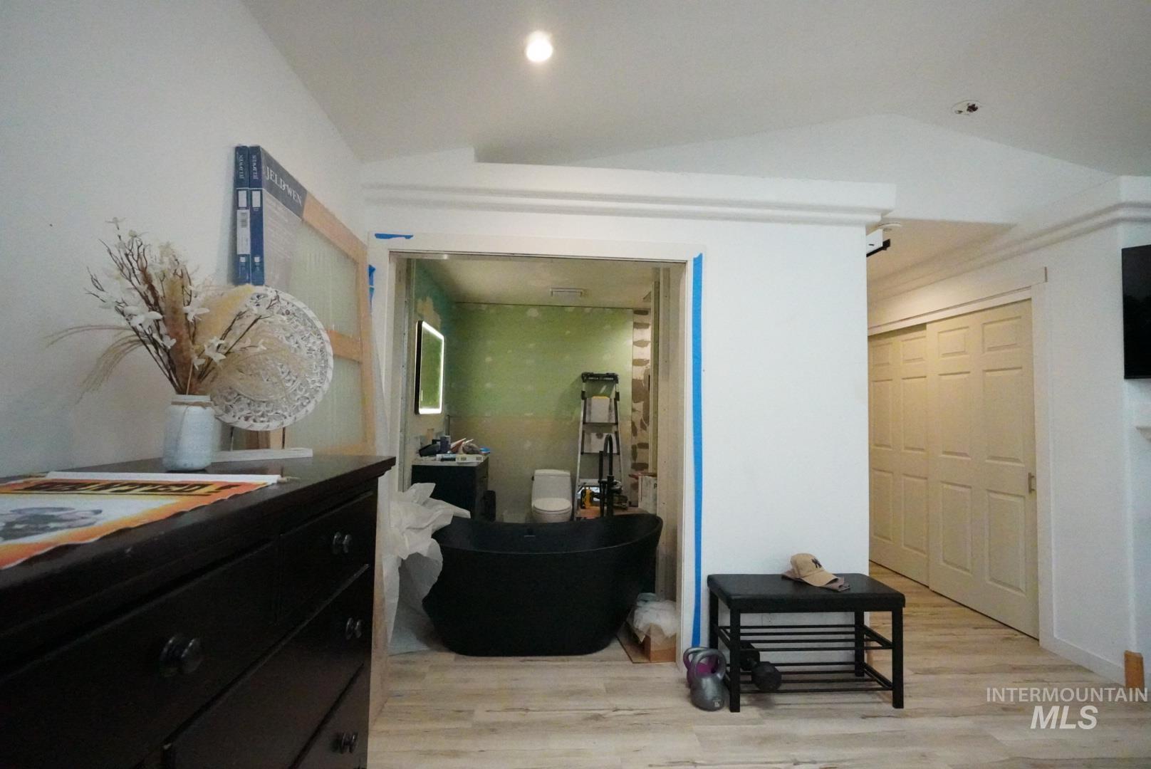 Corridor with light wood-style flooring and lofted ceiling